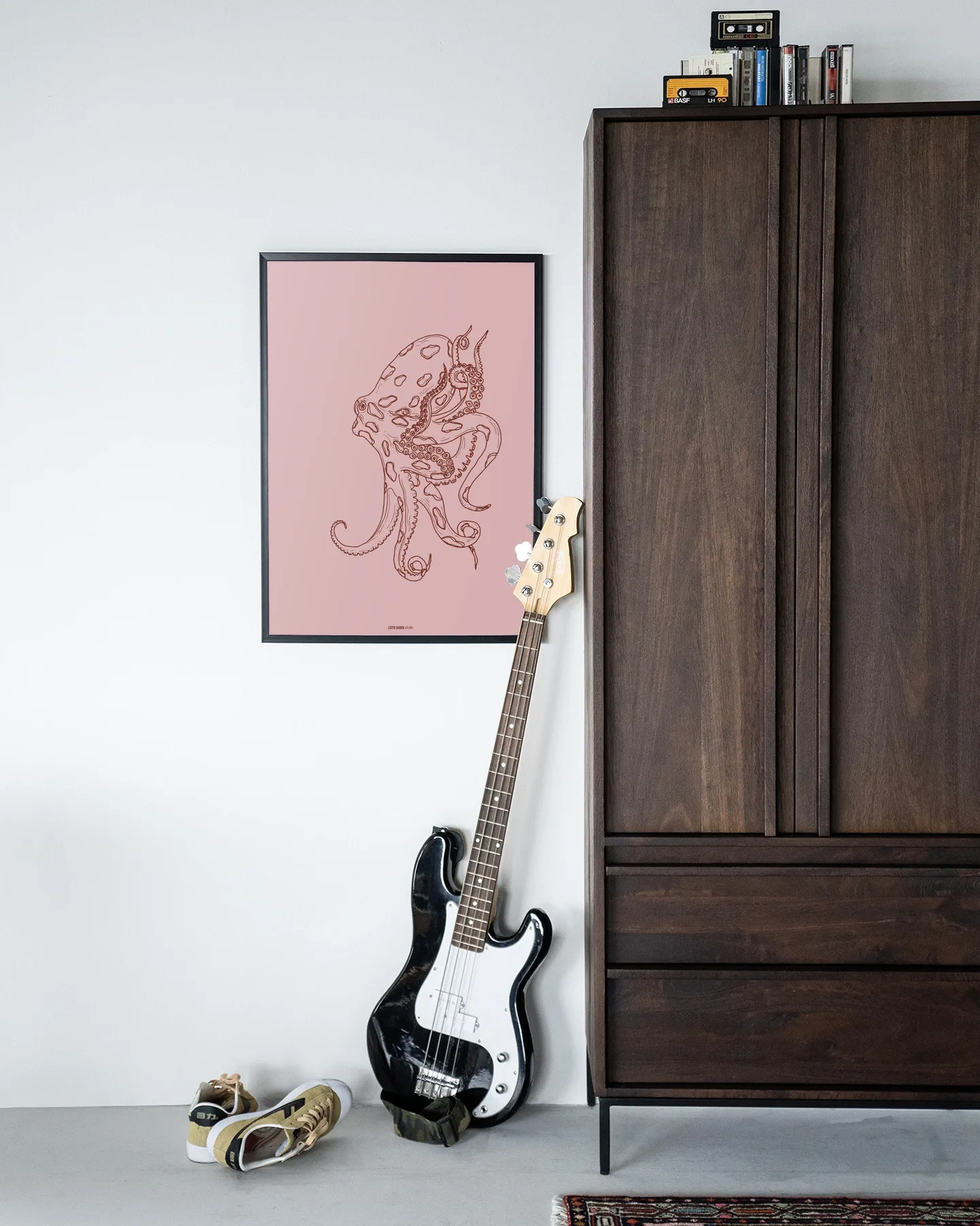 Wandkleed Polypus - Urban Cotton hangt aan een witte muur naast een donkerbruine kast en een basgitaar