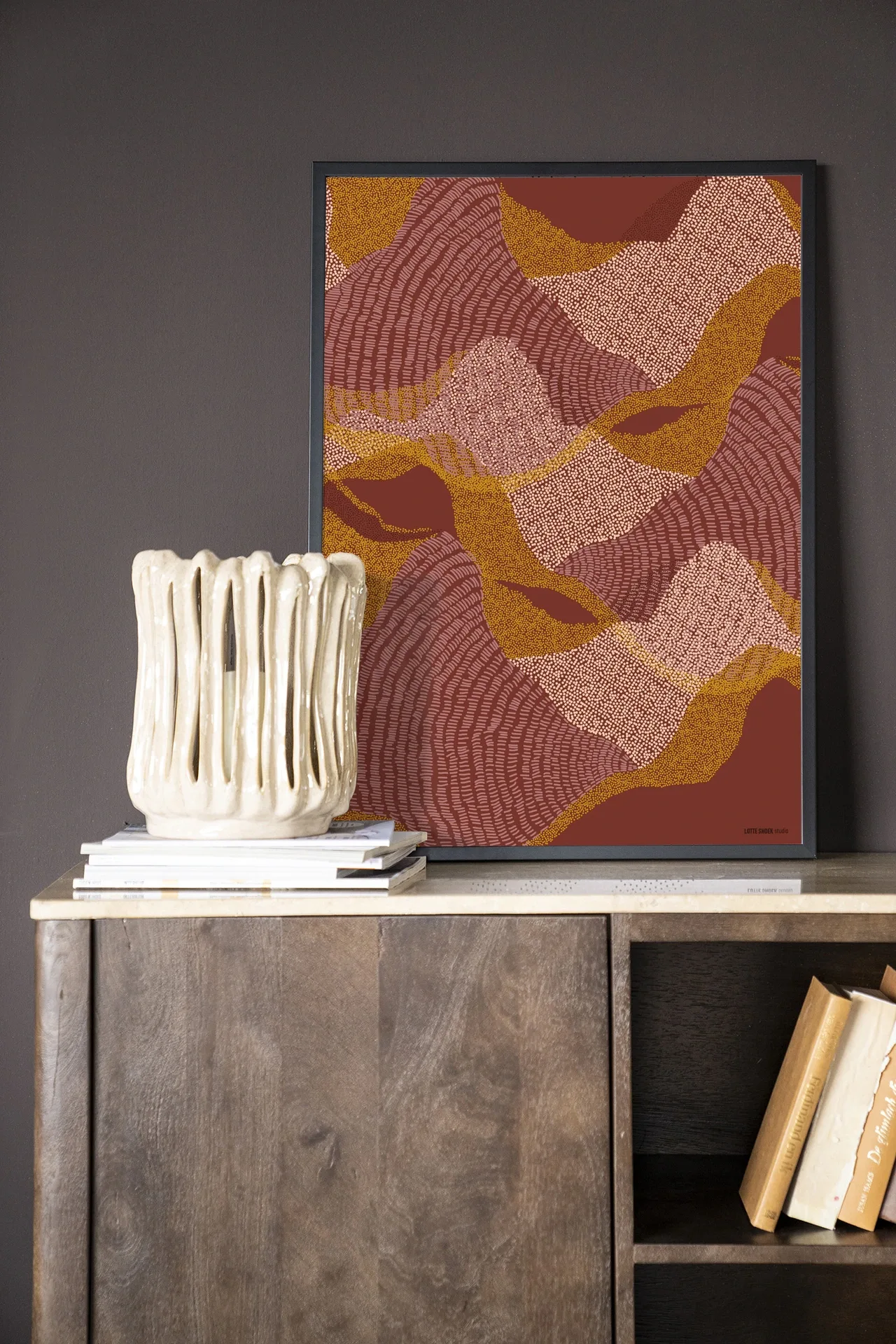 Wandkleed La Ondas - Urban Cotton hangend aan een donkergrijze muur, met een crèmekleurige vaas op een dressoir ervoor