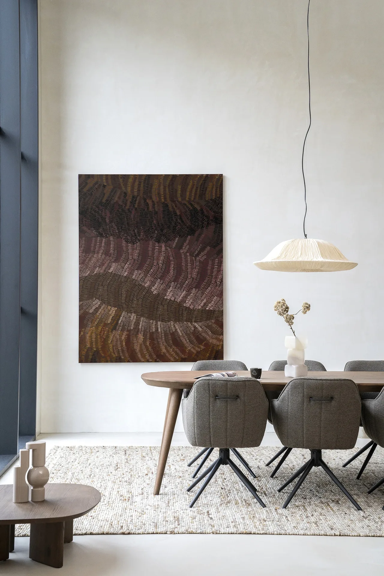Wandkleed Olanan - Urban Cotton hangend aan een witte muur in een modern interieur met eettafel