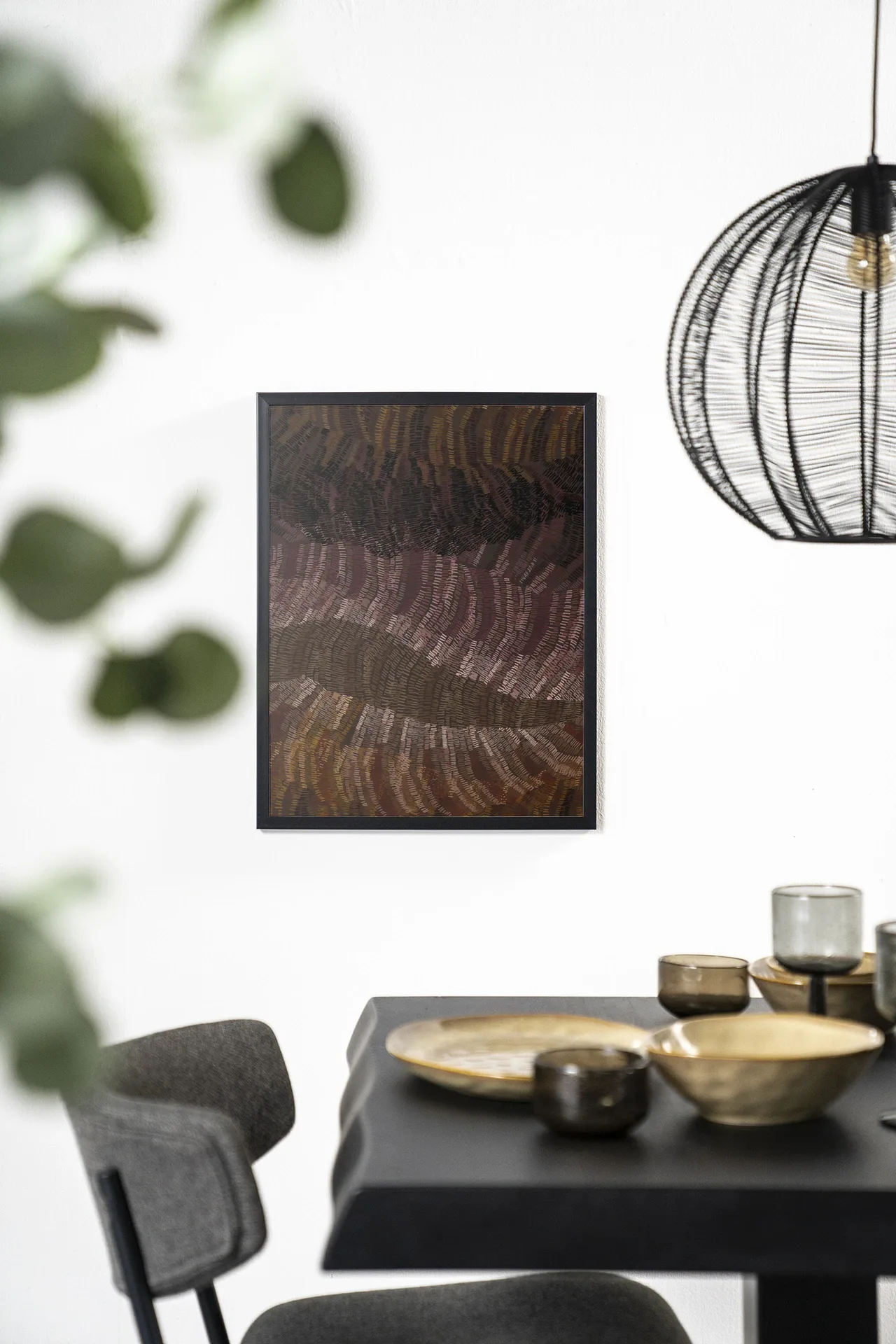 Wandkleed Olanan - Urban Cotton hangt aan een witte muur boven een zwarte eettafel