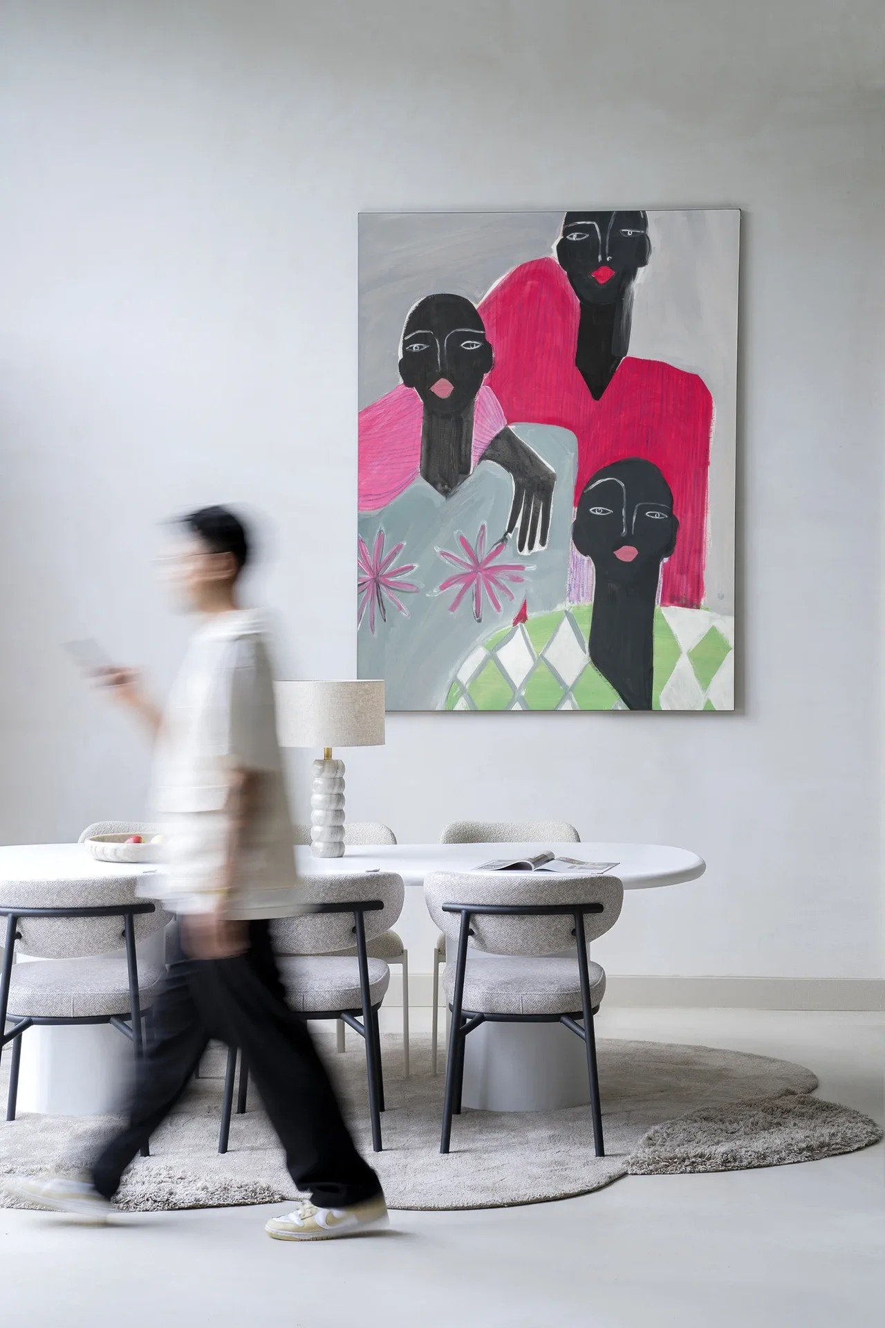 Wandkleed We Are Family hangt aan een witte muur boven een eettafel met stoelen, een persoon loopt langs - Urban Cotton