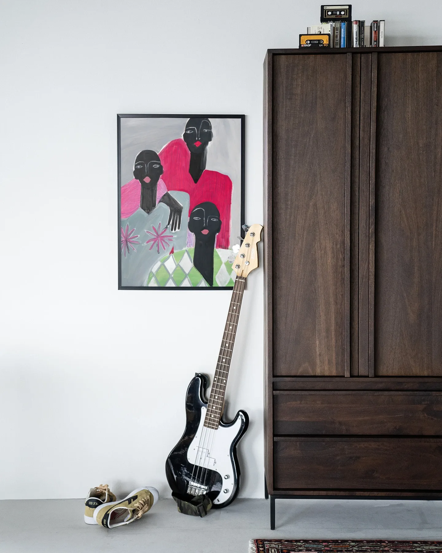 Wandkleed We Are Family hangt aan een witte muur, met een basgitaar en sneakers ervoor - Urban Cotton