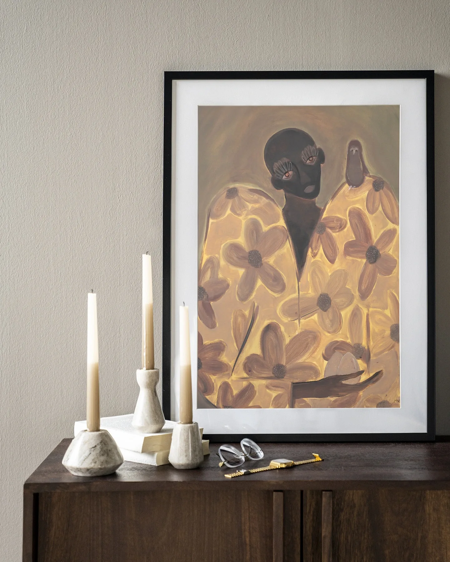 Wandkleed Twins - Urban Cotton hangt boven een houten dressoir met kaarsen en accessoires
