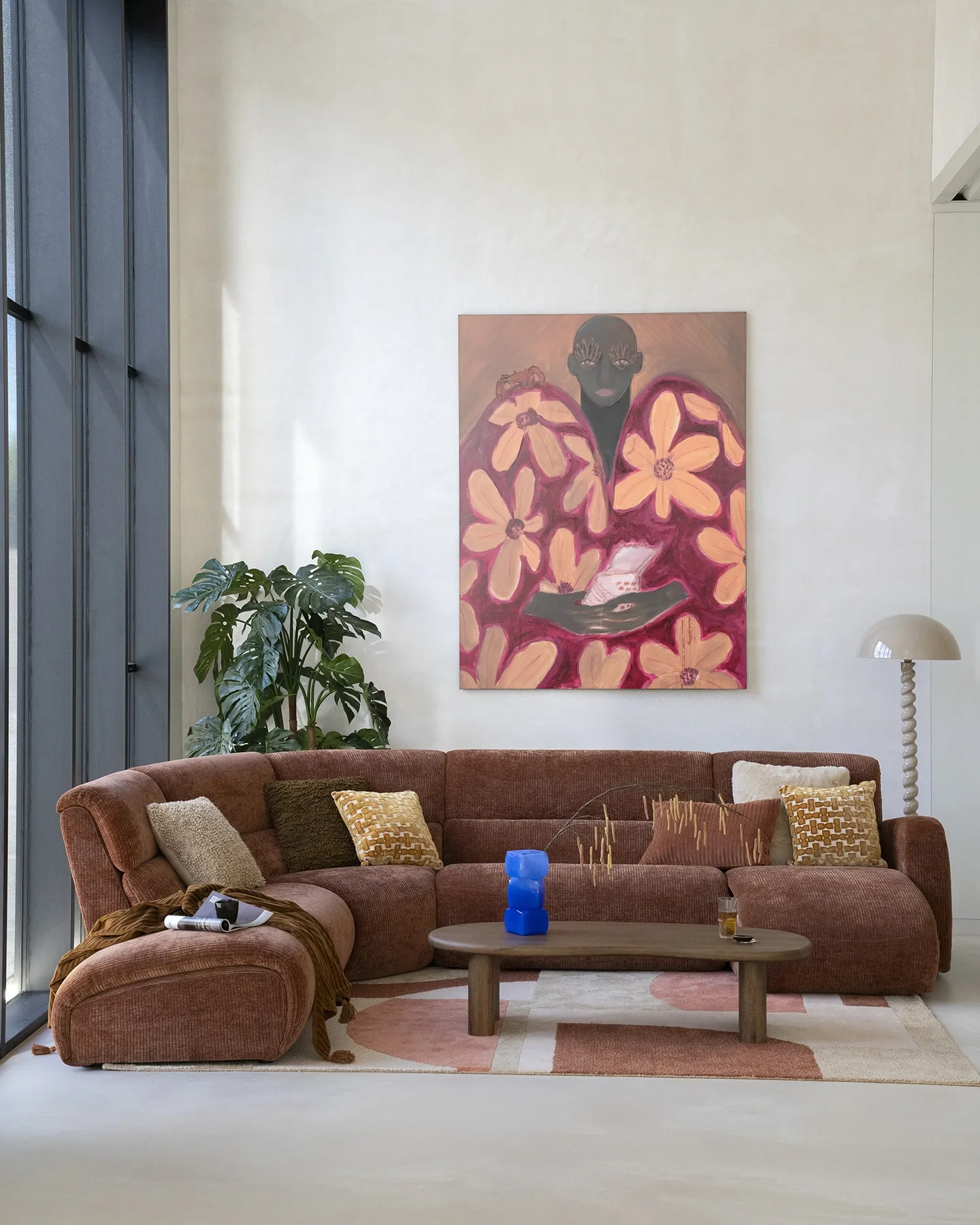 Wandkleed Borrowed Home - Urban Cotton hangt boven een bruine bank in een lichte woonkamer