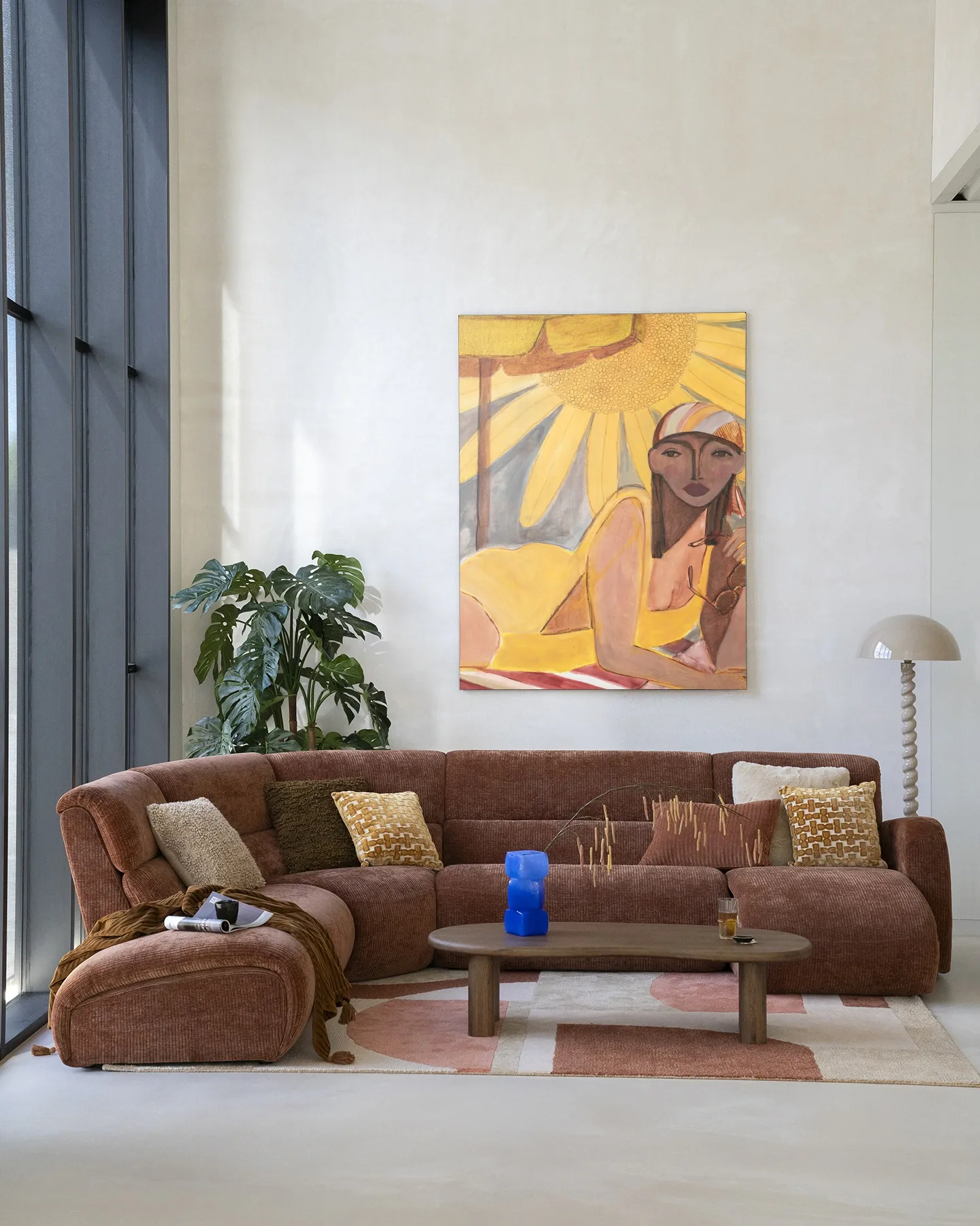 Wandkleed Sunflower Sun hangt boven een bruine bank in een lichte woonkamer met plant - Urban Cotton