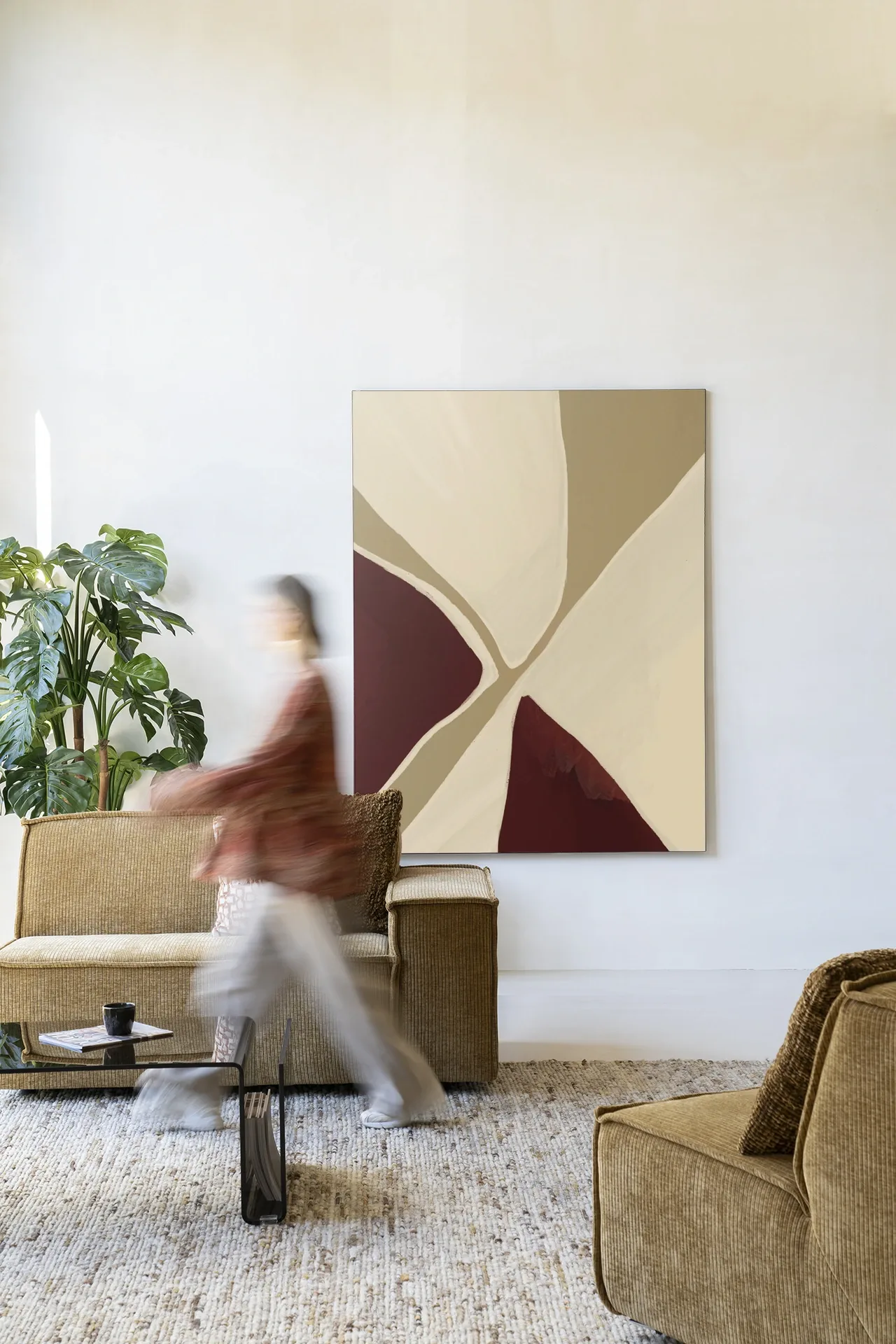 Wandkleed Pandora in een moderne woonkamer met banken en een salontafel, met een persoon die voorbij loopt - Urban Cotton
