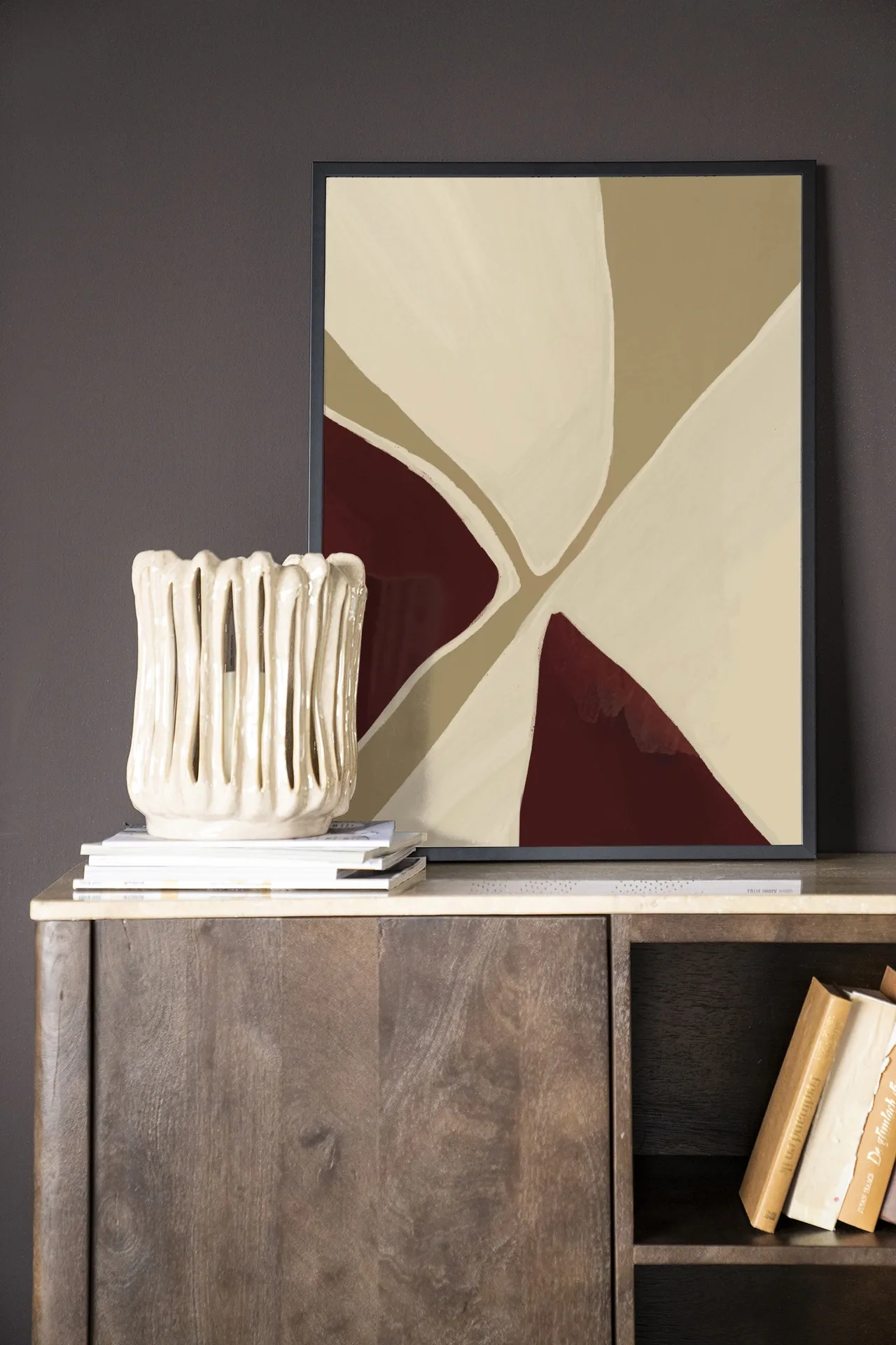 Wandkleed Pandora - Urban Cotton in een lijst, staand op een houten dressoir met boeken