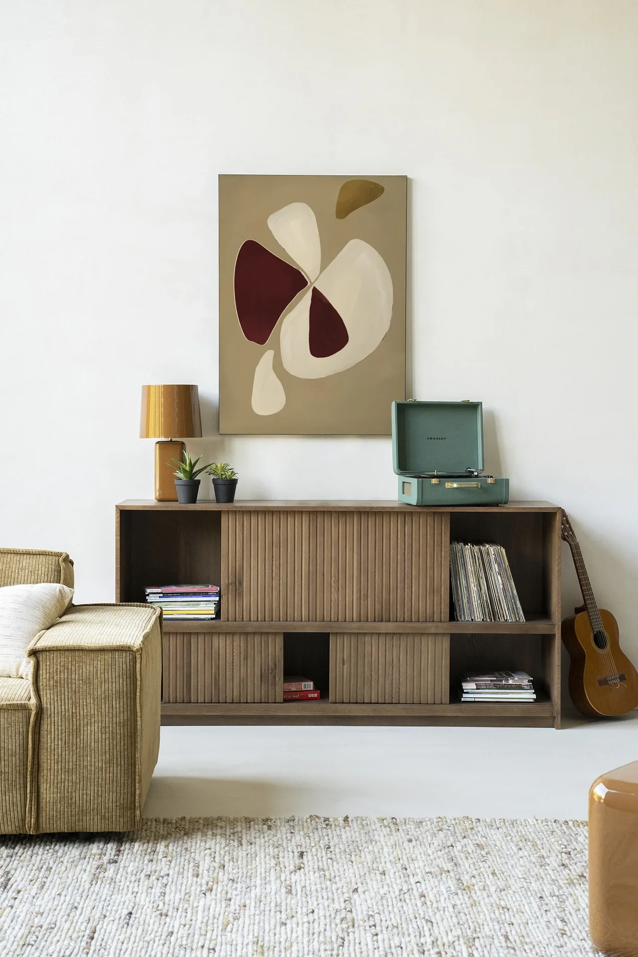 Wandkleed Elegant - Urban Cotton hangt boven een houten dressoir in een sfeervolle woonkamer