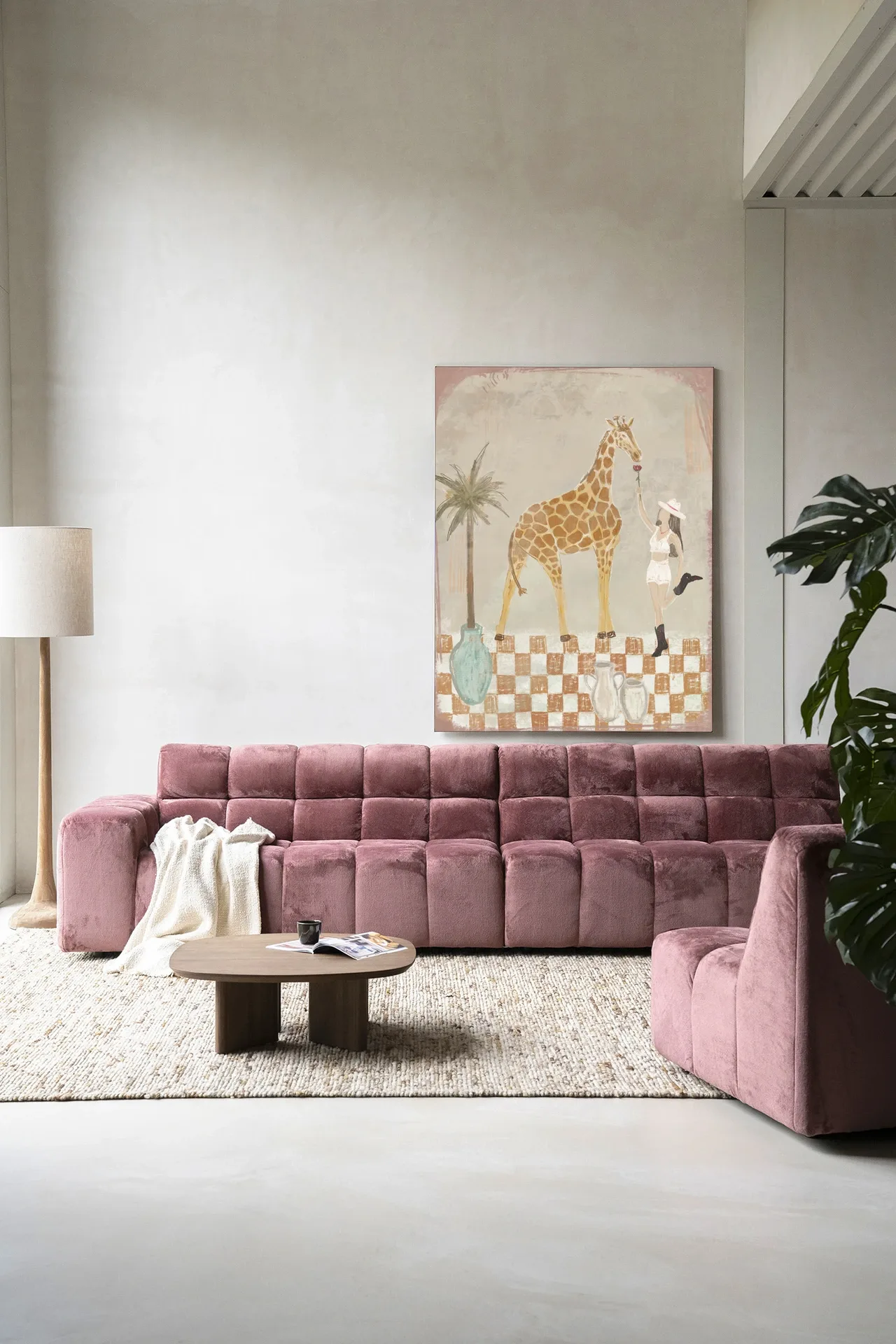 Wandkleed Feeding Rose - Urban Cotton hangt boven een roze bank in een moderne woonkamer