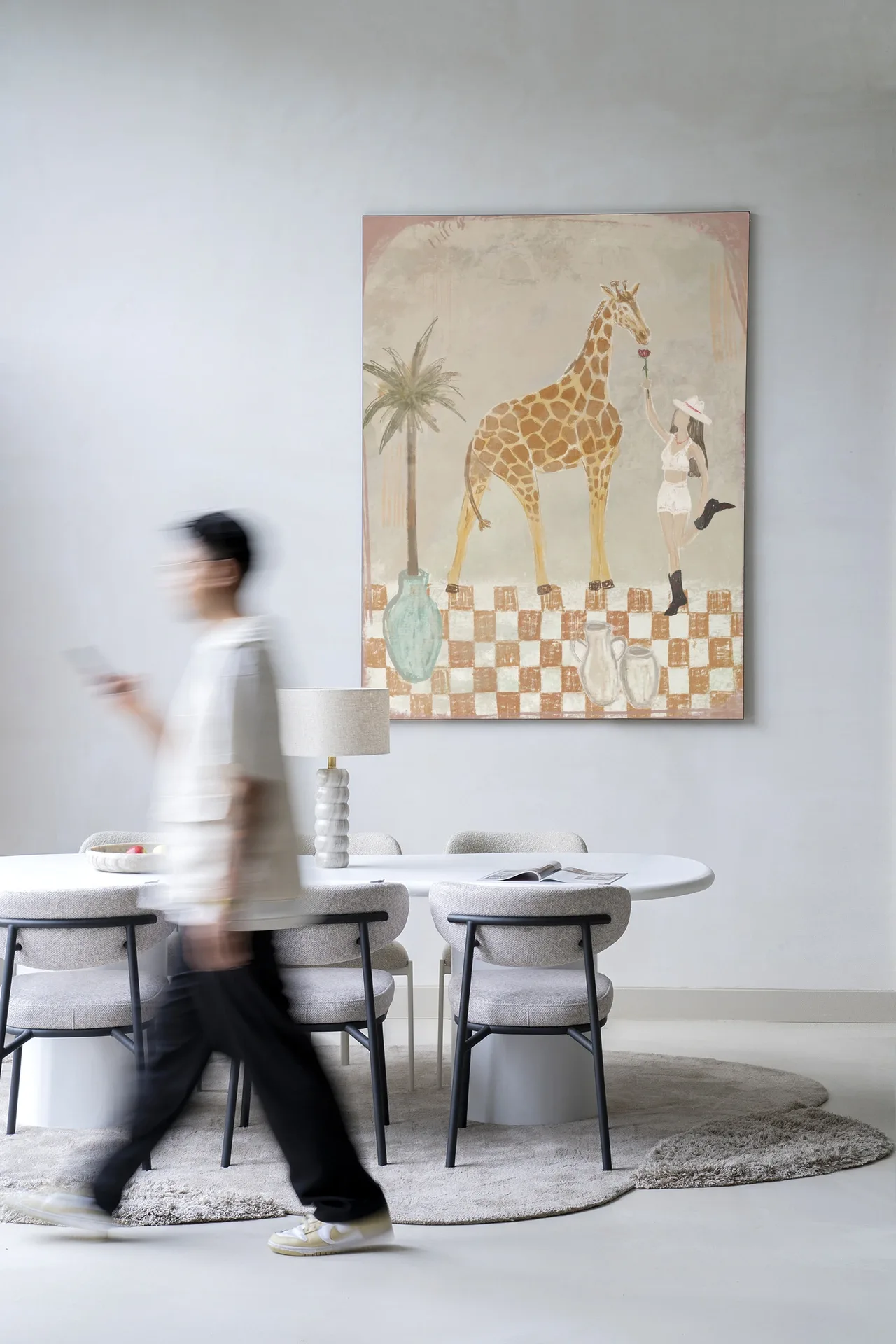 Wandkleed Feeding Rose - Urban Cotton hangt aan een lichte muur boven een eettafel met stoelen