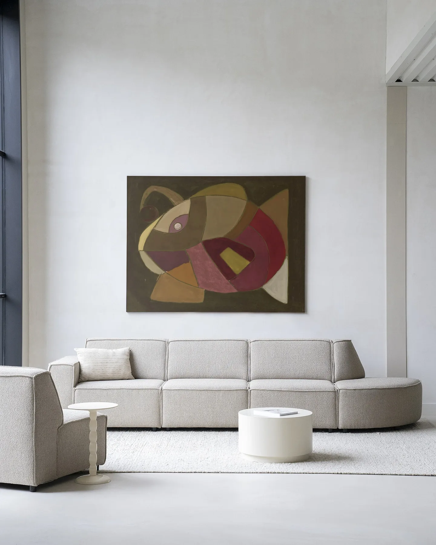 Wandkleed El Pez van Urban Cotton hangend boven een beige bank in een moderne woonkamer