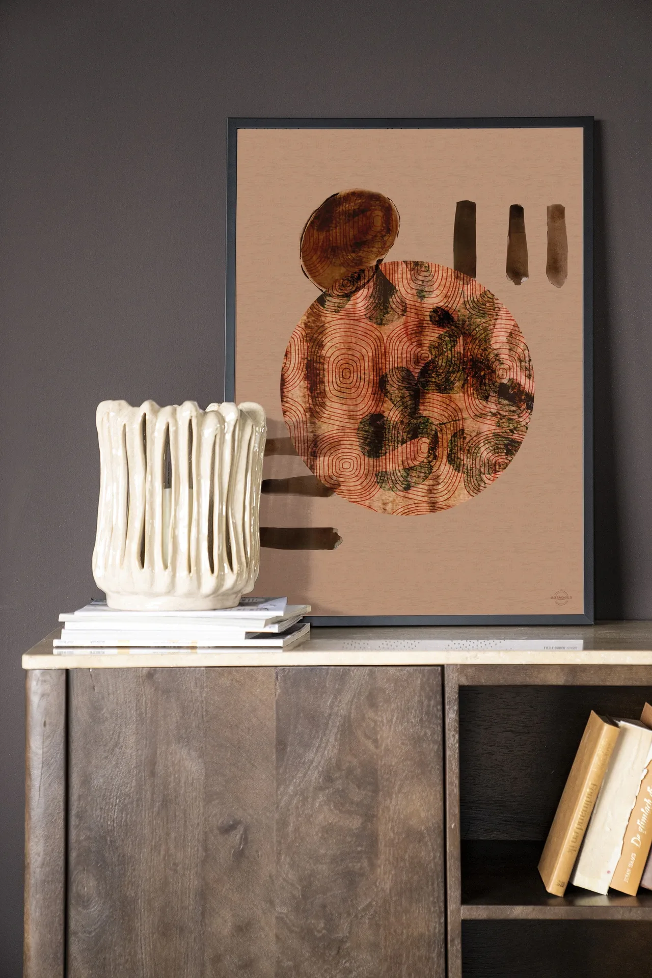 Wandkleed Wabi-Sabi Lifelines - Urban Cotton in een zwarte lijst, staand op een houten dressoir met een vaas en boeken