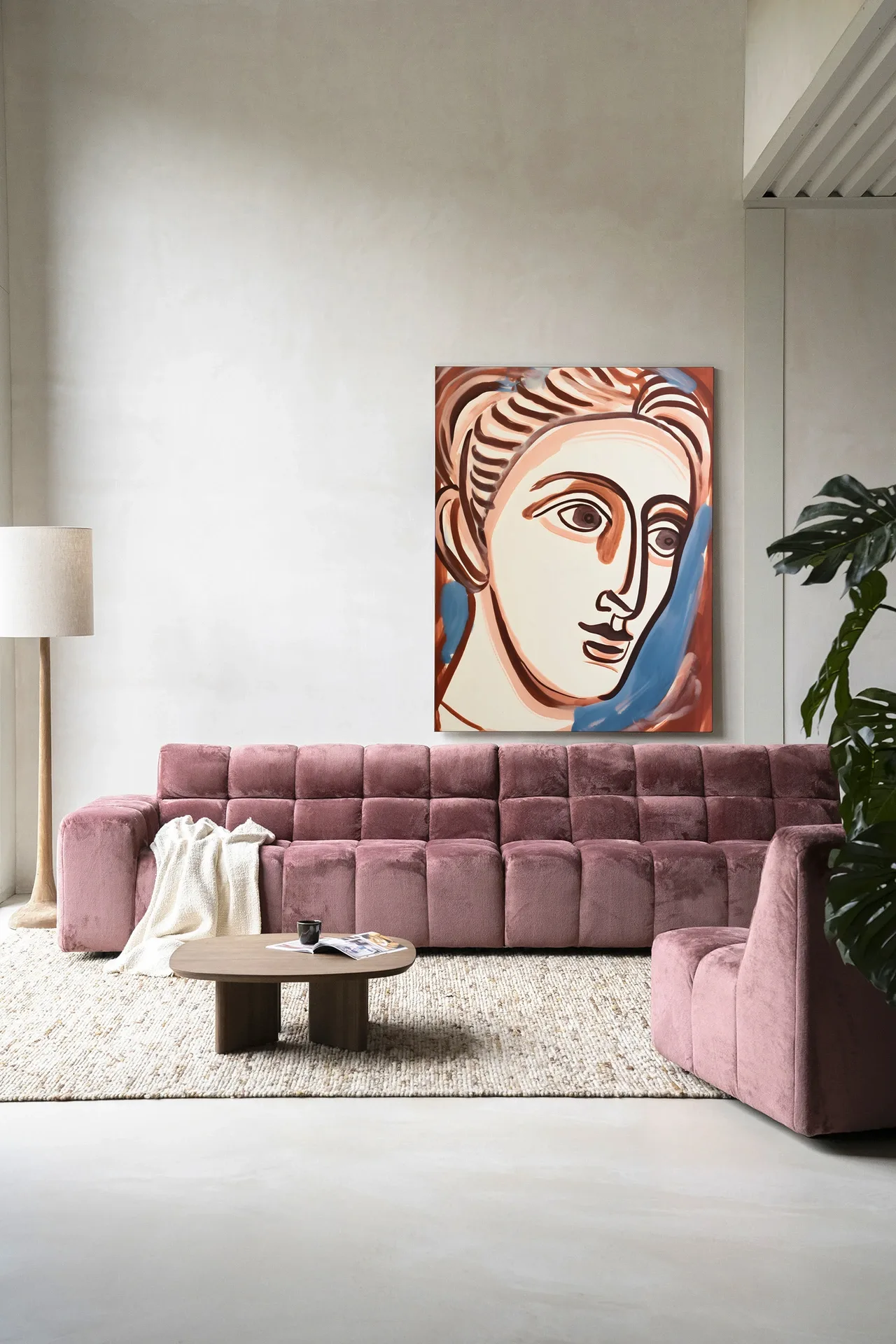Wandkleed Hera - Urban Cotton hangend boven een roze bank in een moderne woonkamer