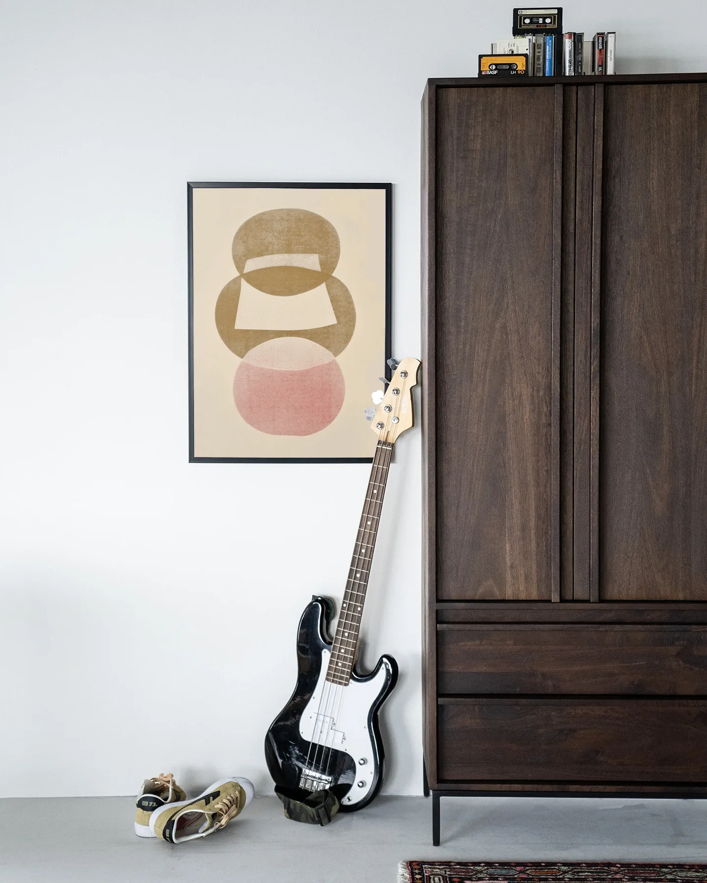 Art print Figuras 1 - Urban Cotton hangend aan een witte muur, met een basgitaar en schoenen ervoor