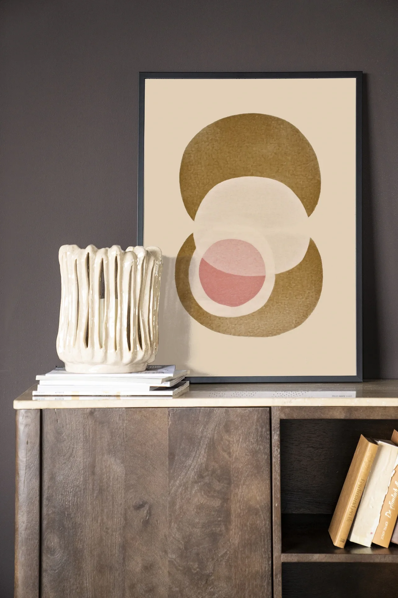 Art print Figuras 2 - Urban Cotton in een zwarte lijst op een houten dressoir met een vaas