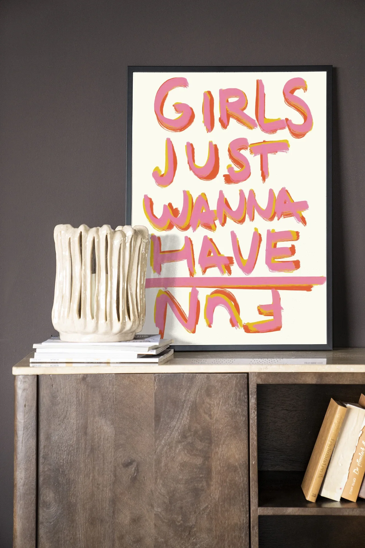 Wandkleed P.S Written By A Girl - Urban Cotton in een zwarte lijst, staand op een houten dressoir