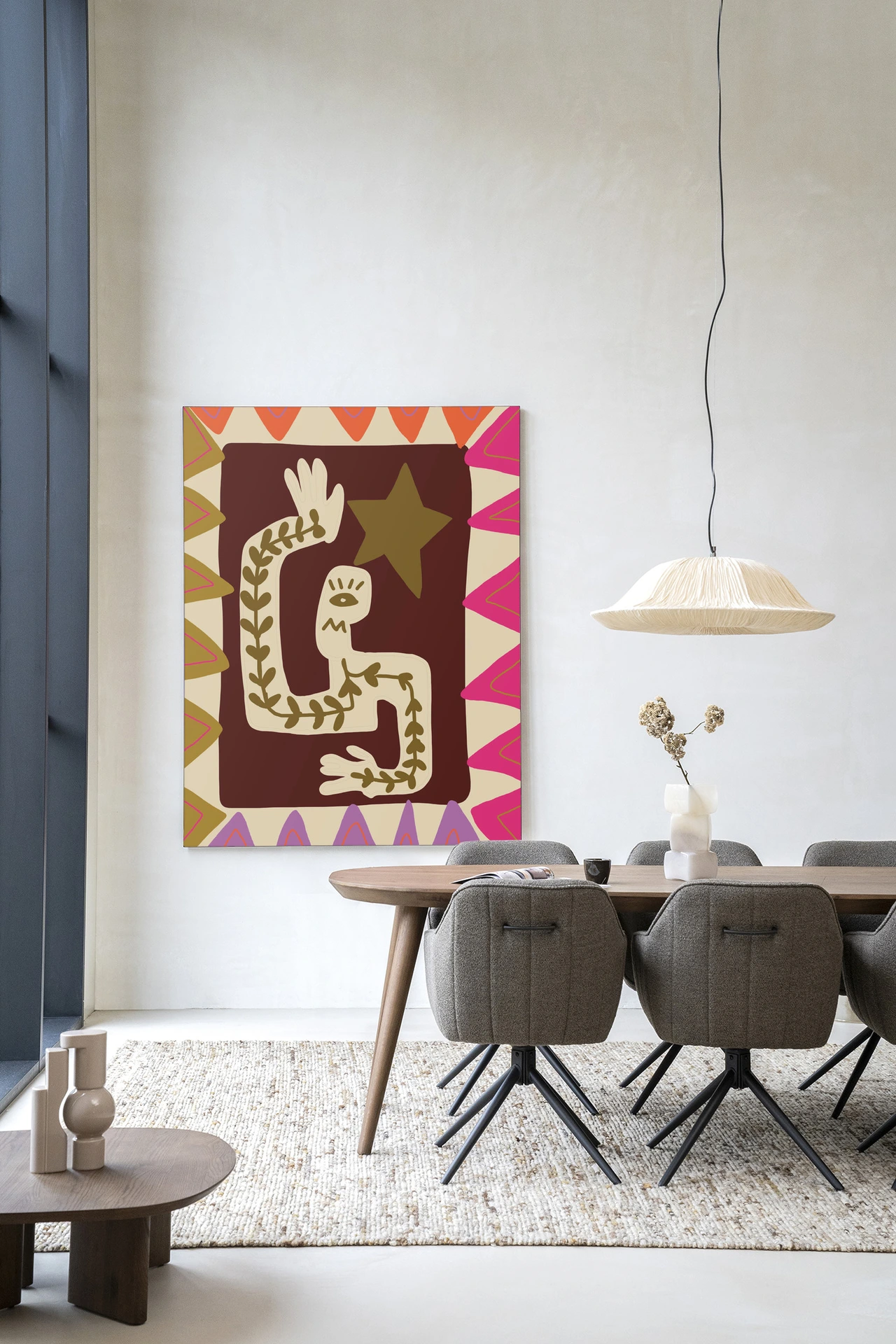 Wandkleed Wave van Urban Cotton hangt aan een witte muur boven een houten eettafel met grijze stoelen