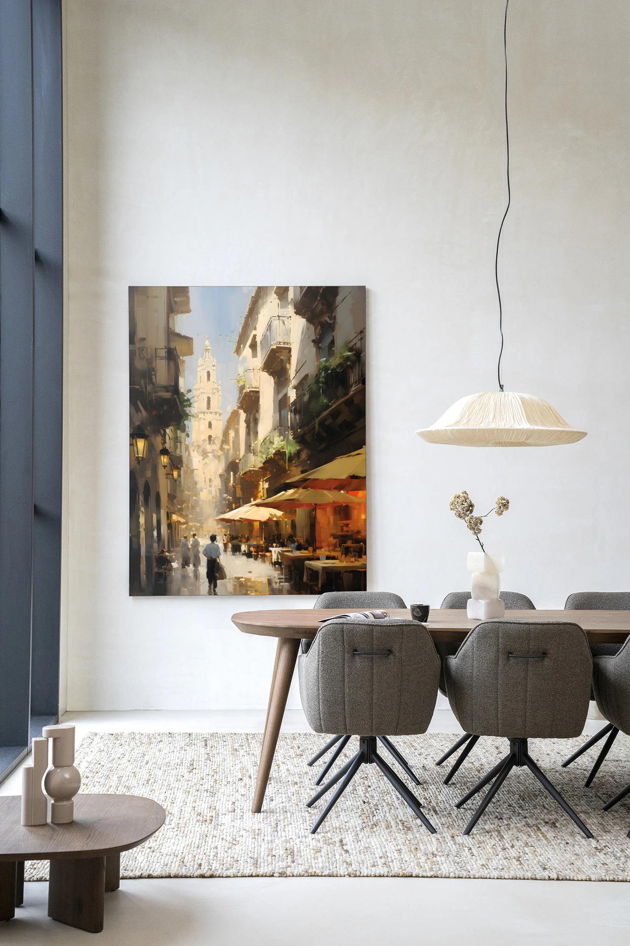 Wandkleed Barcelona - Urban Cotton hangt aan een witte muur boven een houten eettafel met grijze stoelen