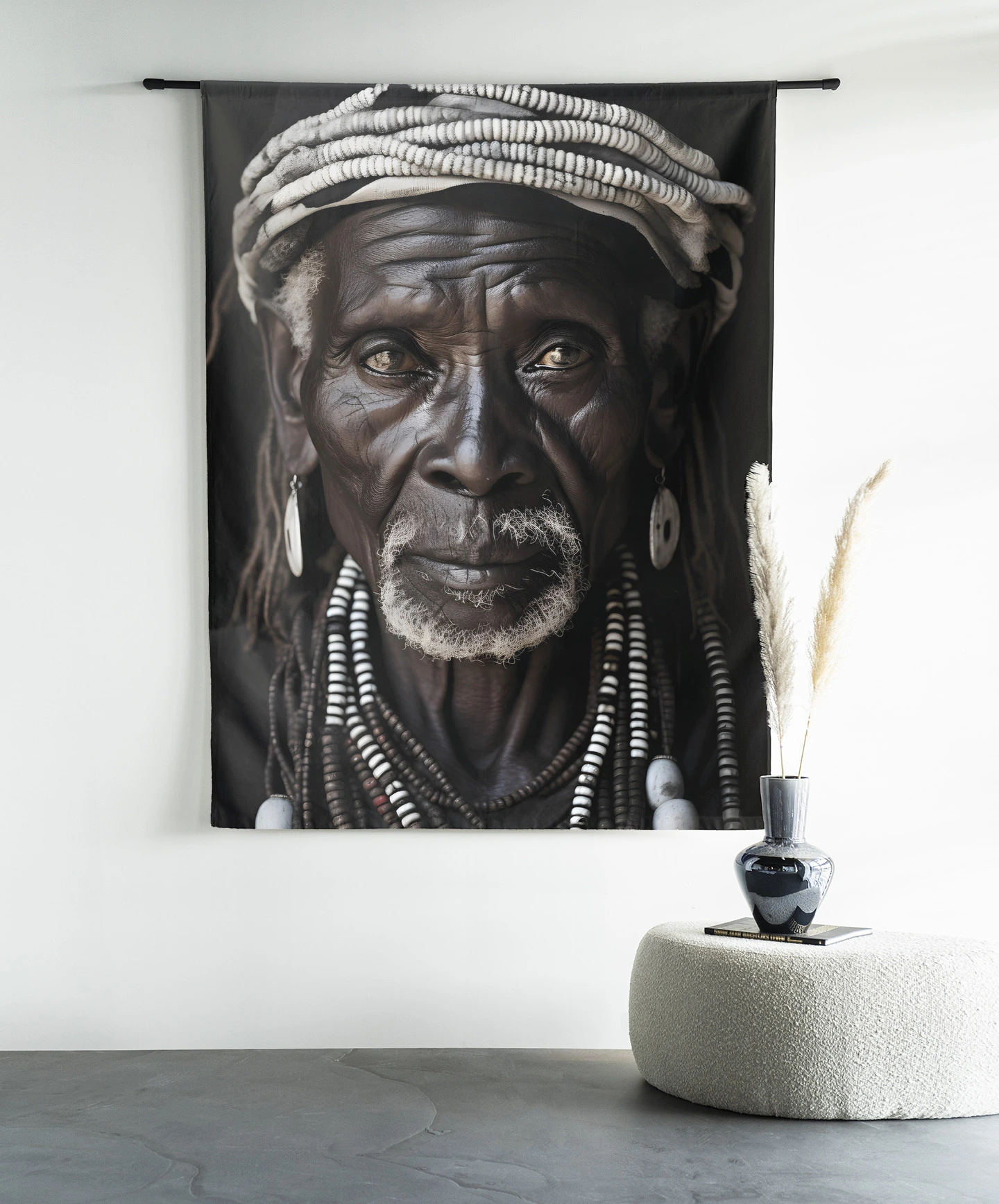 Wandkleed Kabila hangt aan een zwarte roede boven een witte poef met een vaas en boeken - Urban Cotton