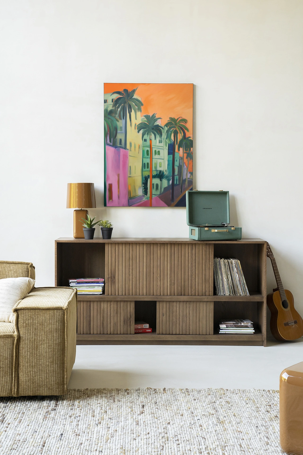 Wandkleed Palm Street - Urban Cotton hangt boven een houten dressoir in een sfeervolle woonkamer