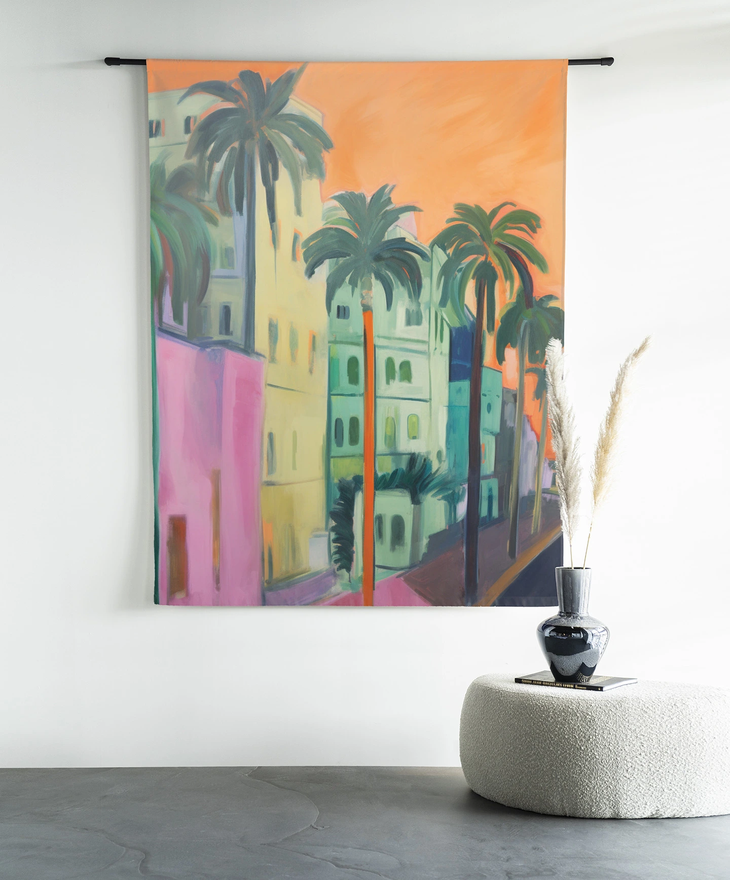 Een wandkleed Palm Street - Urban Cotton hangt aan een zwarte roede boven een poef met decoratie