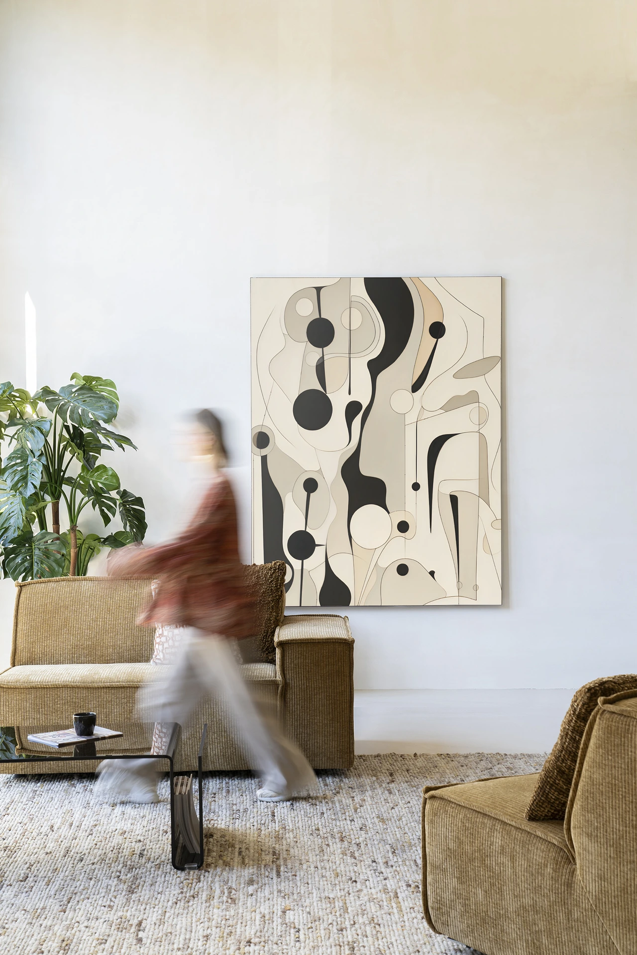 Wandkleed Toulouse - Urban Cotton hangt aan een witte muur in een modern interieur met bank en salontafel
