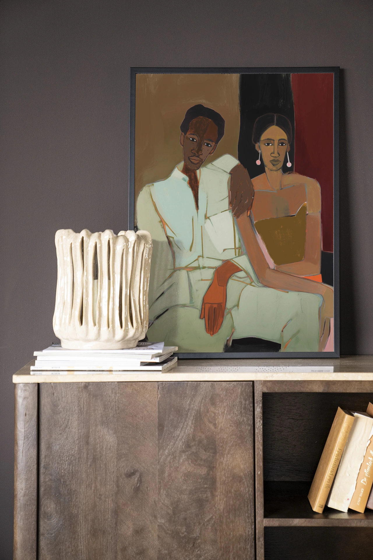 Wandkleed Parental - Urban Cotton hangt boven een houten dressoir met een vaas en boeken