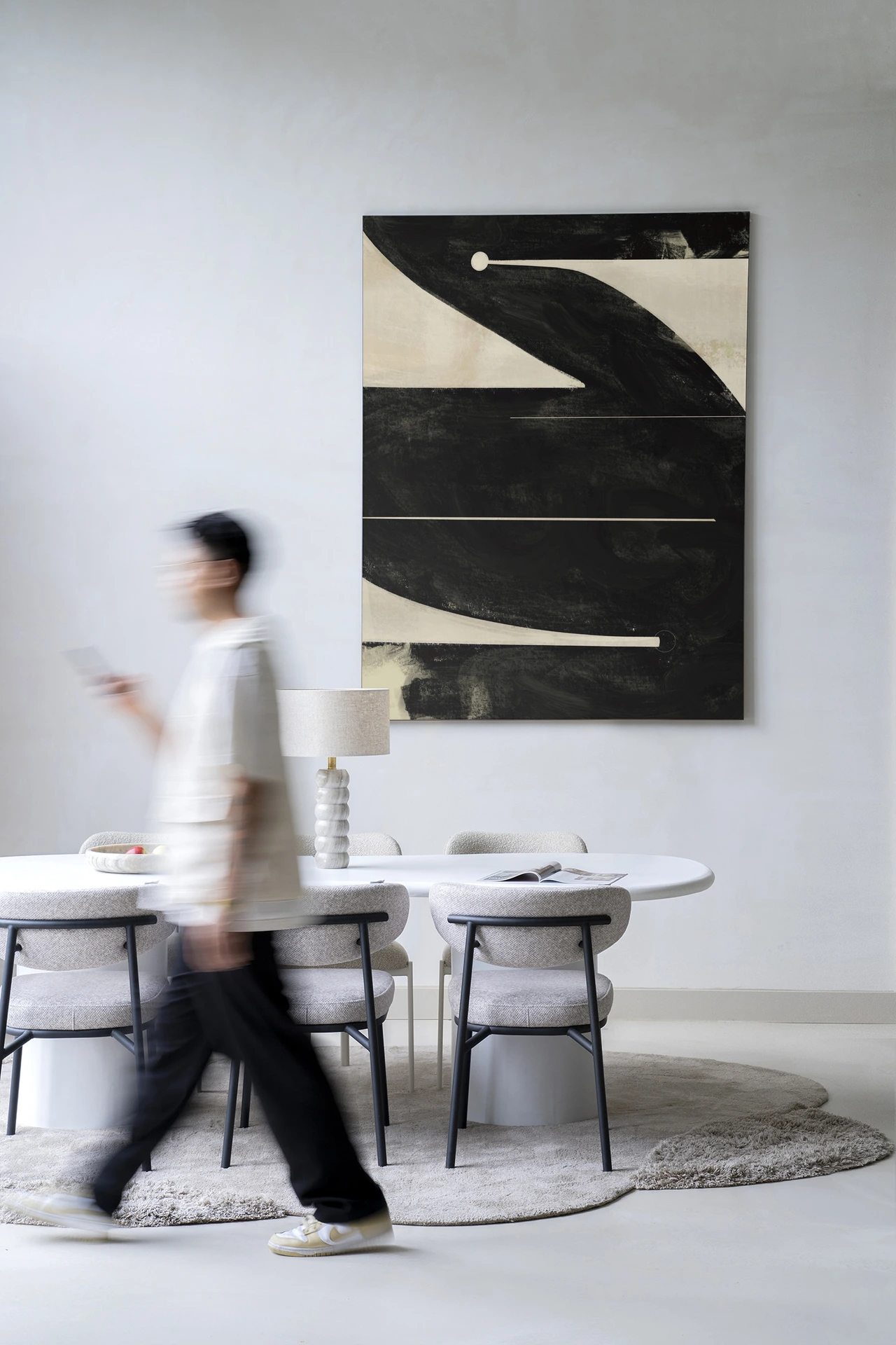 Wandkleed Nocturne Oasis hangt boven een eettafel met stoelen, een lamp en een persoon die voorbijloopt - Urban Cotton