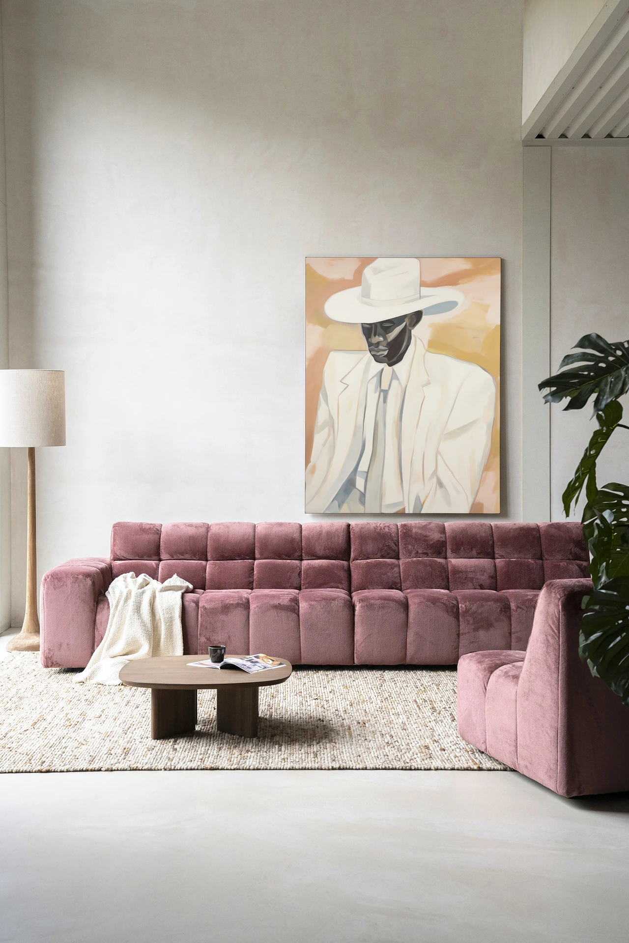Wandkleed Dusty Don - Urban Cotton hangt boven een roze bank in een moderne woonkamer