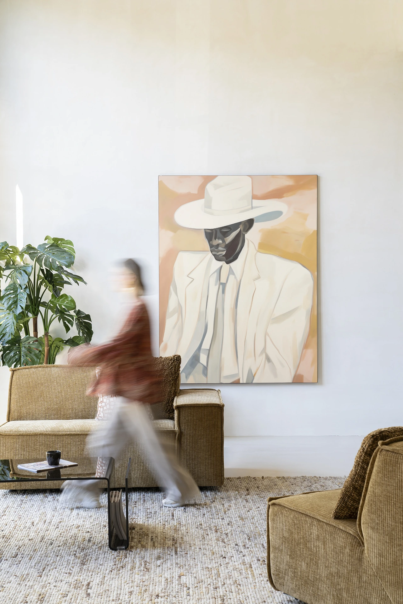 Wandkleed Dusty Don - Urban Cotton hangt aan een witte muur in een woonkamer met een persoon in beweging