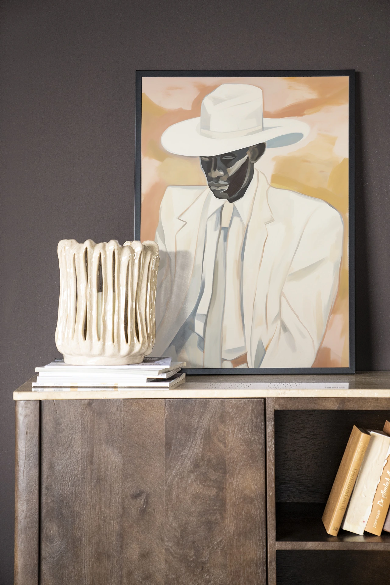 Wandkleed Dusty Don - Urban Cotton hangt boven een houten kast met een vaas en boeken