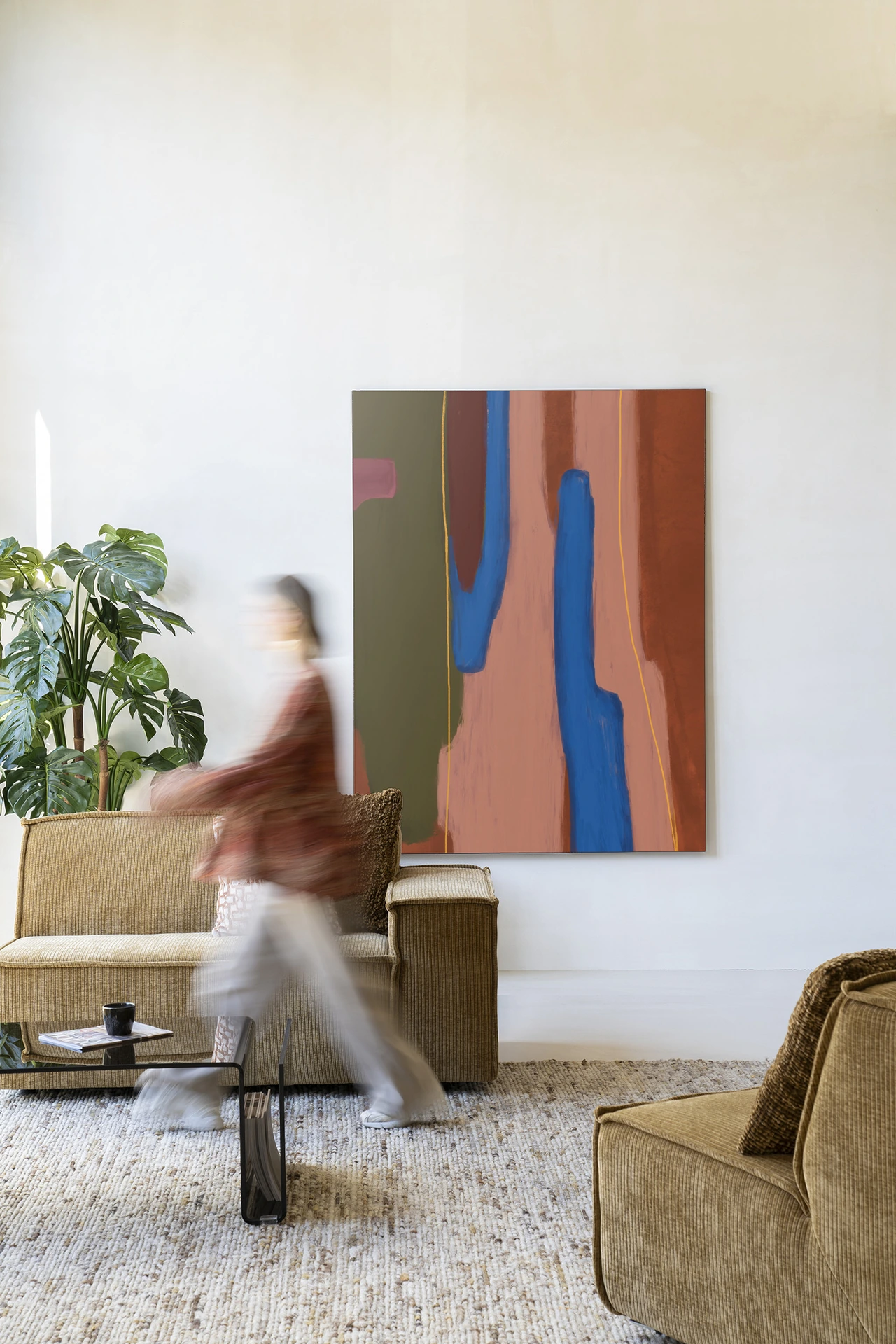 Wandkleed Tajo van Urban Cotton hangt aan een witte muur in een modern interieur met een persoon in beweging