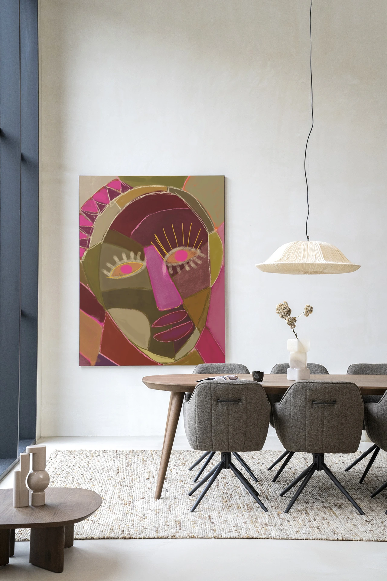 Wandkleed Mas Que Nada - Urban Cotton hangt aan een witte muur boven een houten eettafel met grijze stoelen