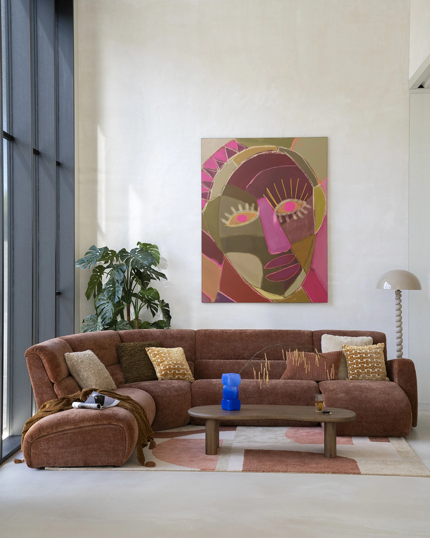 Wandkleed Mas Que Nada - Urban Cotton hangt boven een bruine ribfluwelen hoekbank in een lichte woonkamer