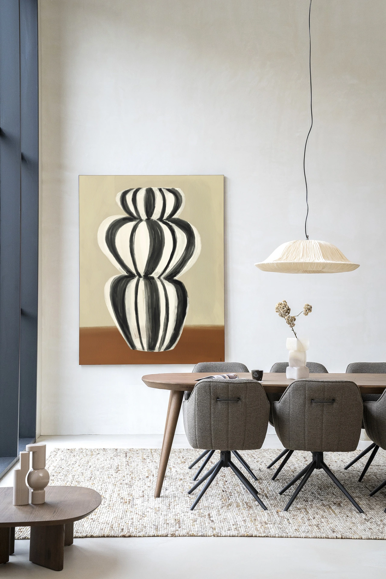 Wandkleed Vivid Vase 03 - Urban Cotton hangend boven een houten eettafel met grijze stoelen in een modern interieur