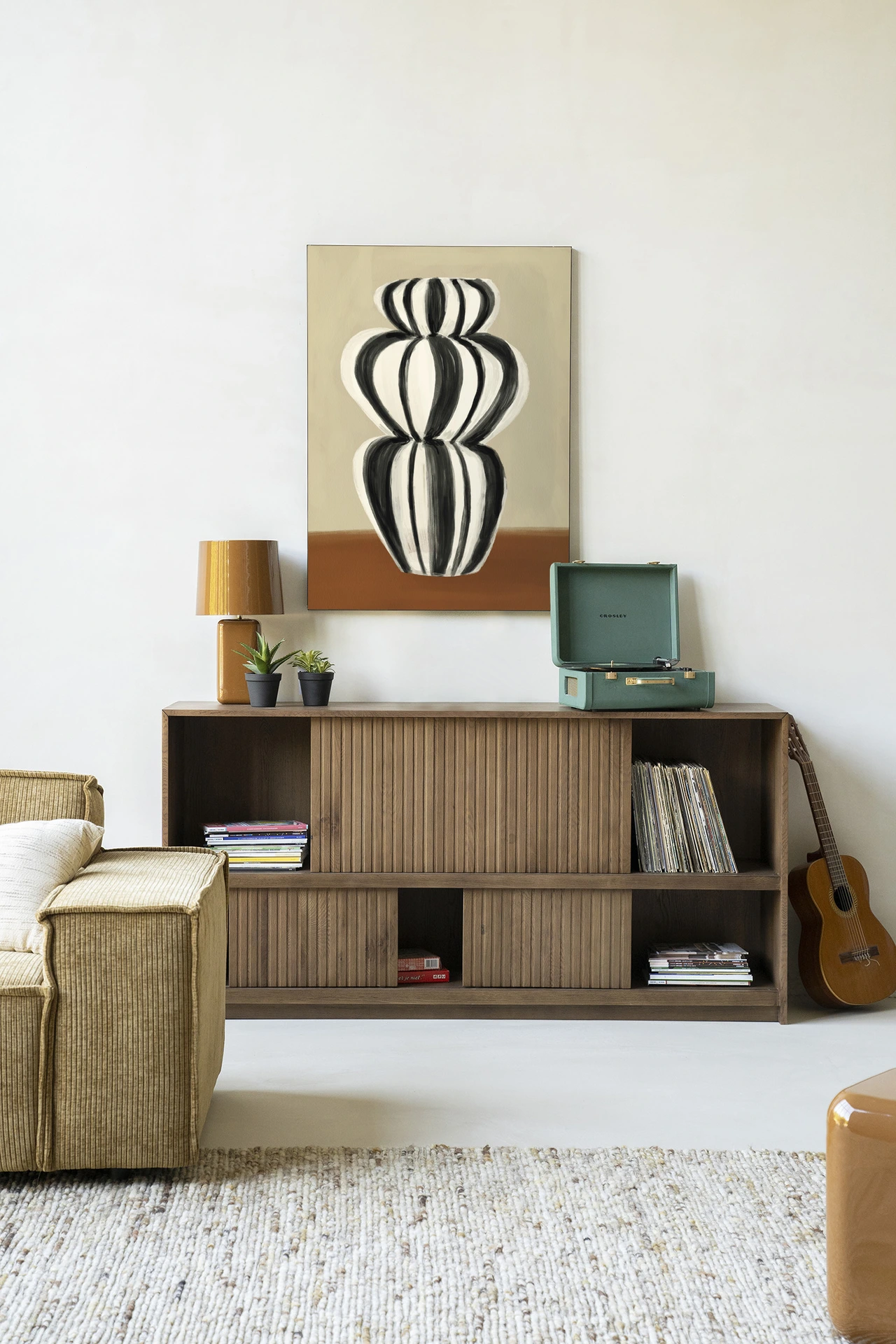 Wandkleed Vivid Vase 03 - Urban Cotton hangt boven een houten dressoir met een platenspeler en plantjes