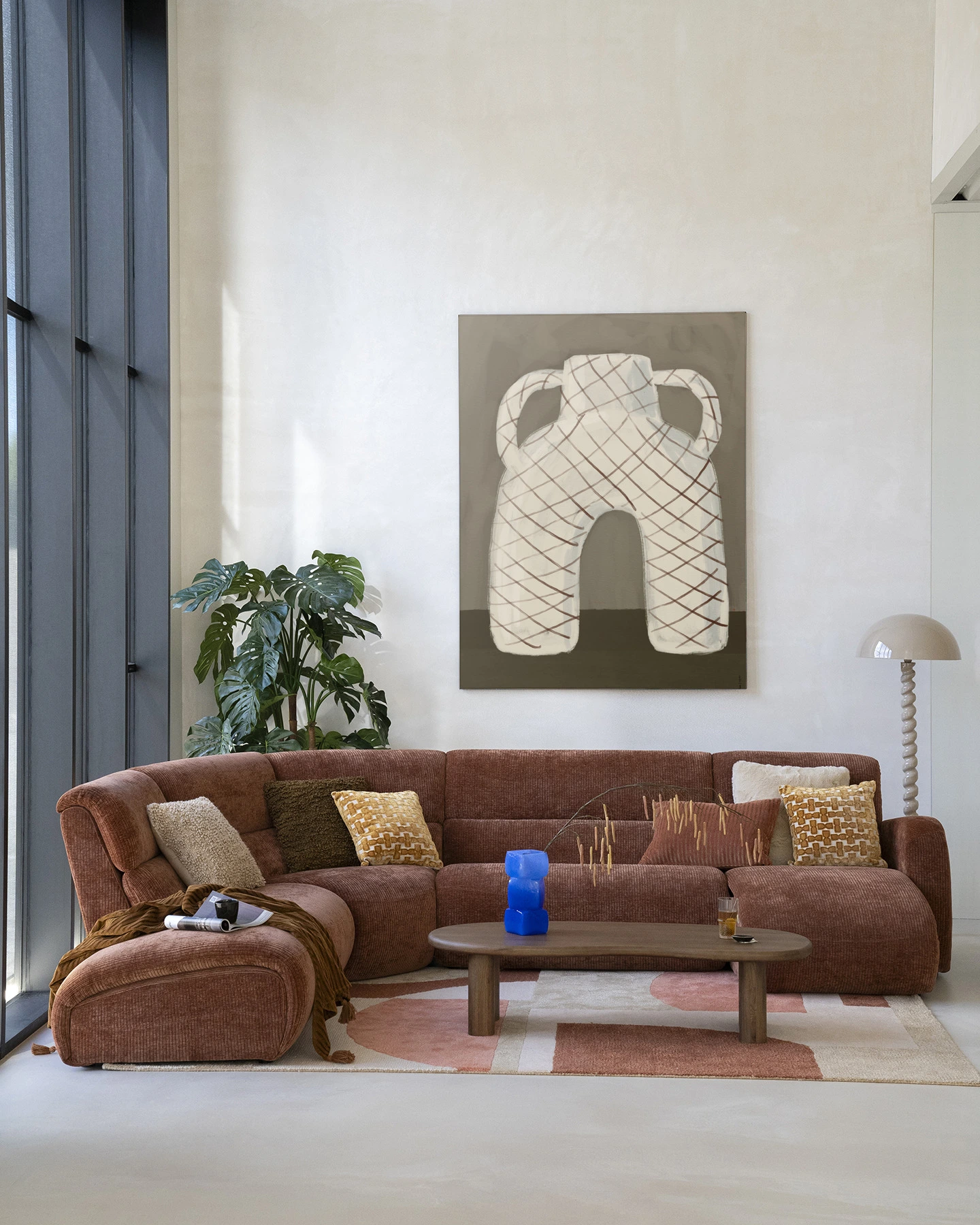 Wandkleed Vivid Vase 05 - Urban Cotton hangt boven een bruine ribfluwelen hoekbank in een lichte woonkamer