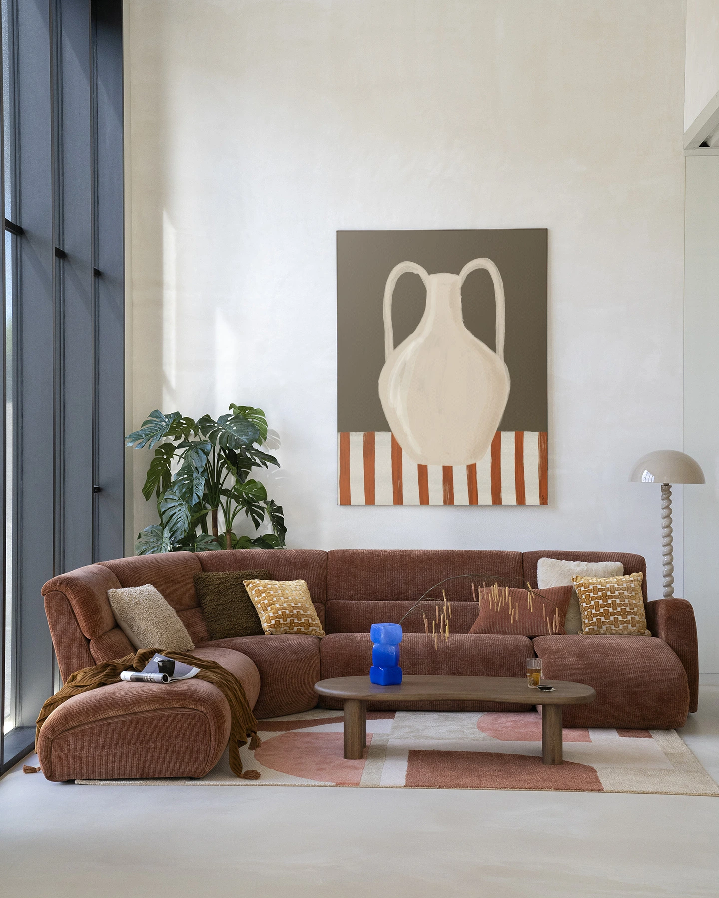 Wandkleed Vivid Vase 06 - Urban Cotton hangt boven een bruine bank in een moderne woonkamer