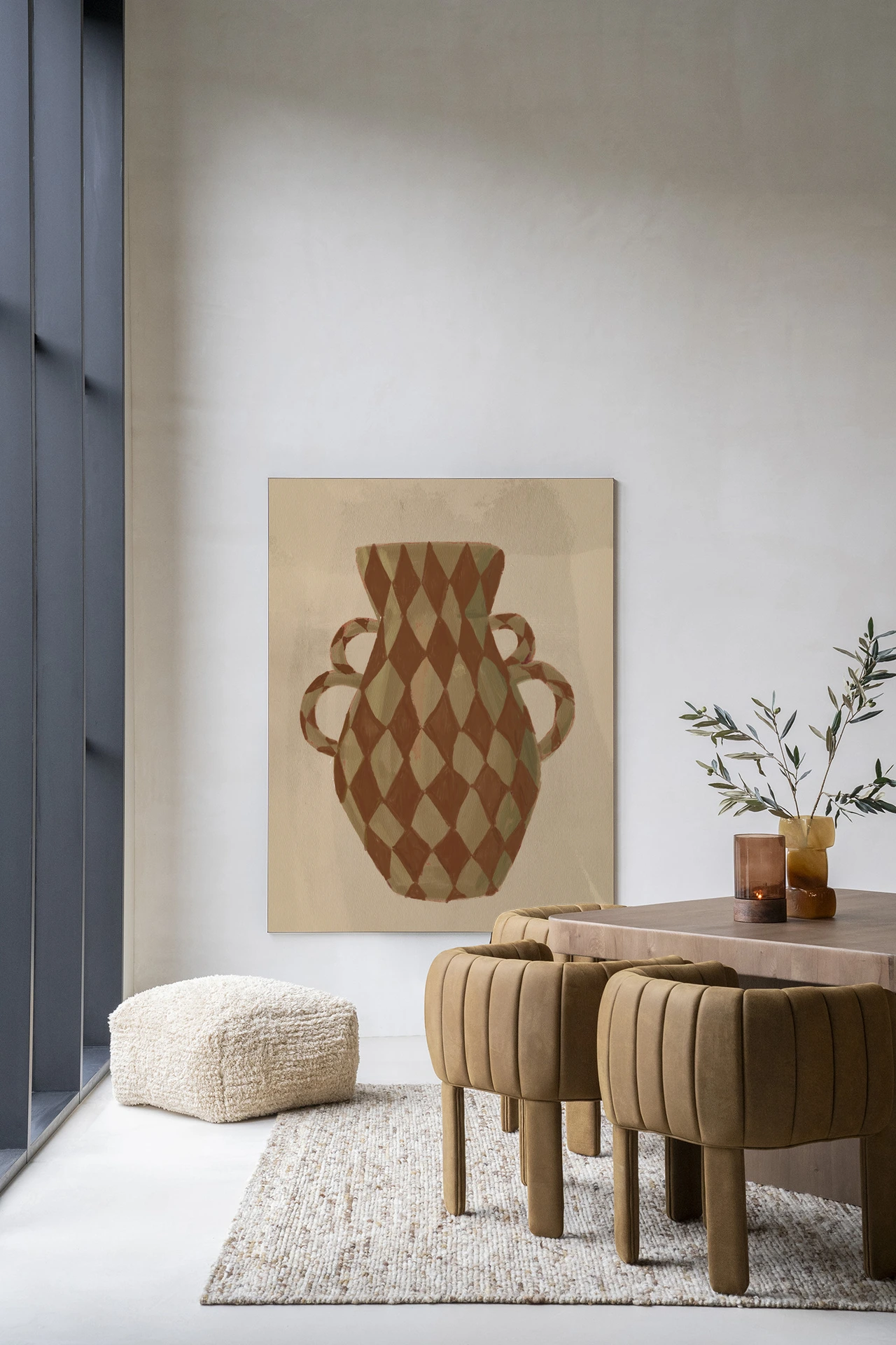 Wandkleed Vivid Vase 08 - Urban Cotton hangt aan een lichte muur in een modern interieur met een poef en stoelen