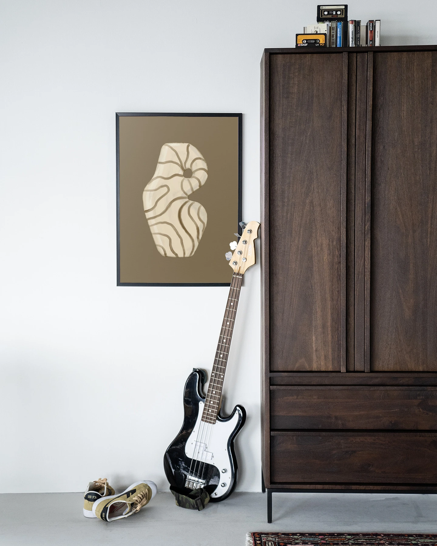 Wandkleed Vivid Vase 09 - Urban Cotton hangt aan een witte muur naast een donkerhouten kast met een basgitaar ervoor