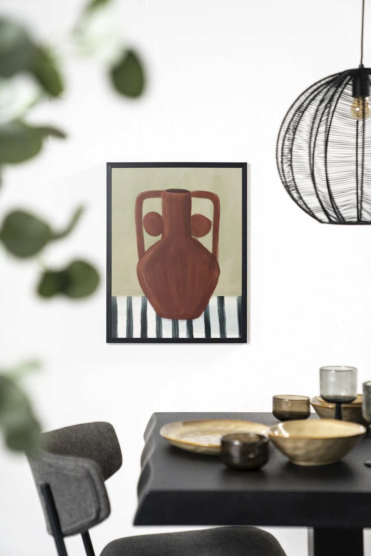 Wandkleed Vivid Vase 10 - Urban Cotton hangt aan een witte muur boven een zwarte tafel