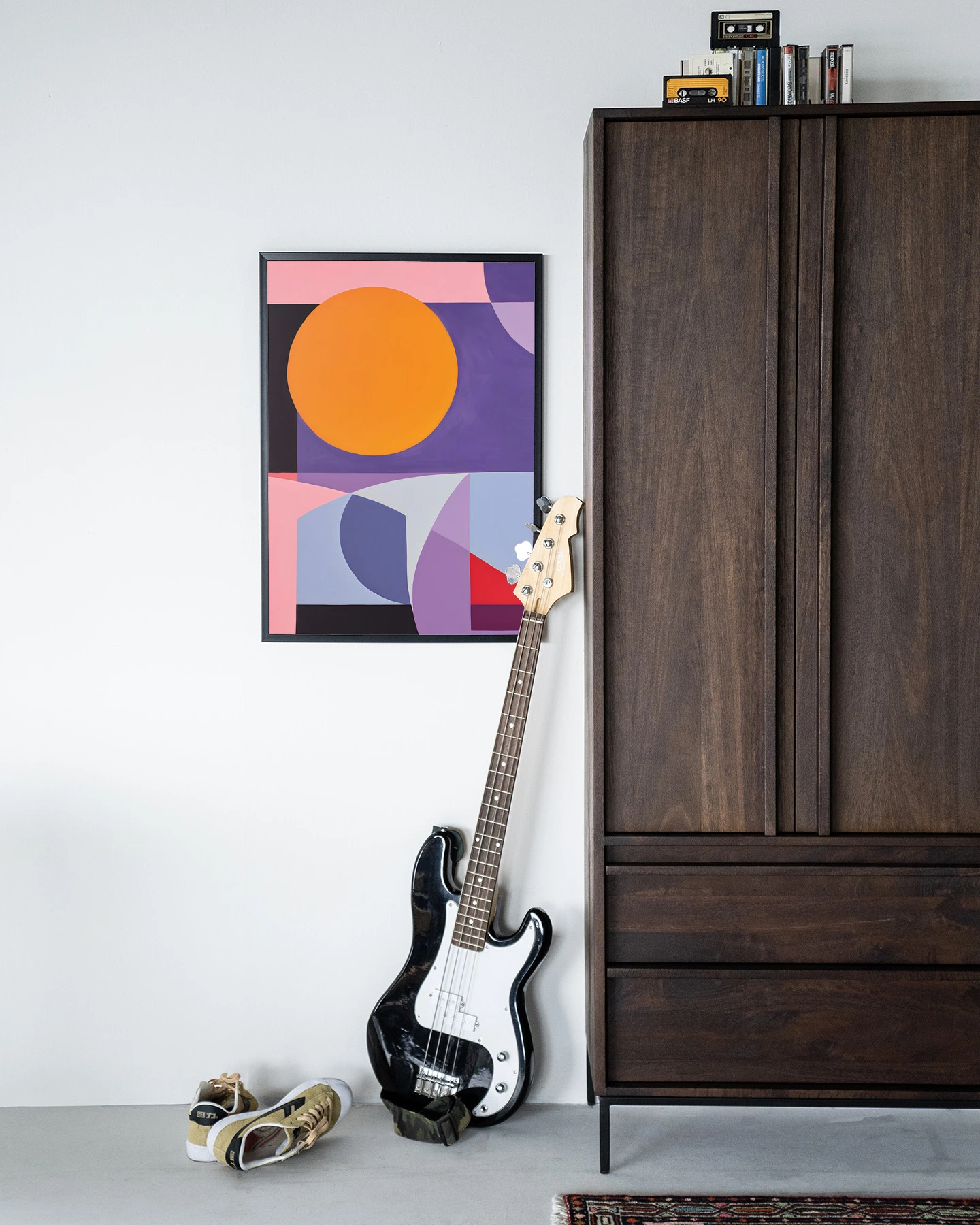 Wandkleed Repulsive - Urban Cotton hangend aan een witte muur naast een donkerbruine kast met een basgitaar en schoenen ervoor