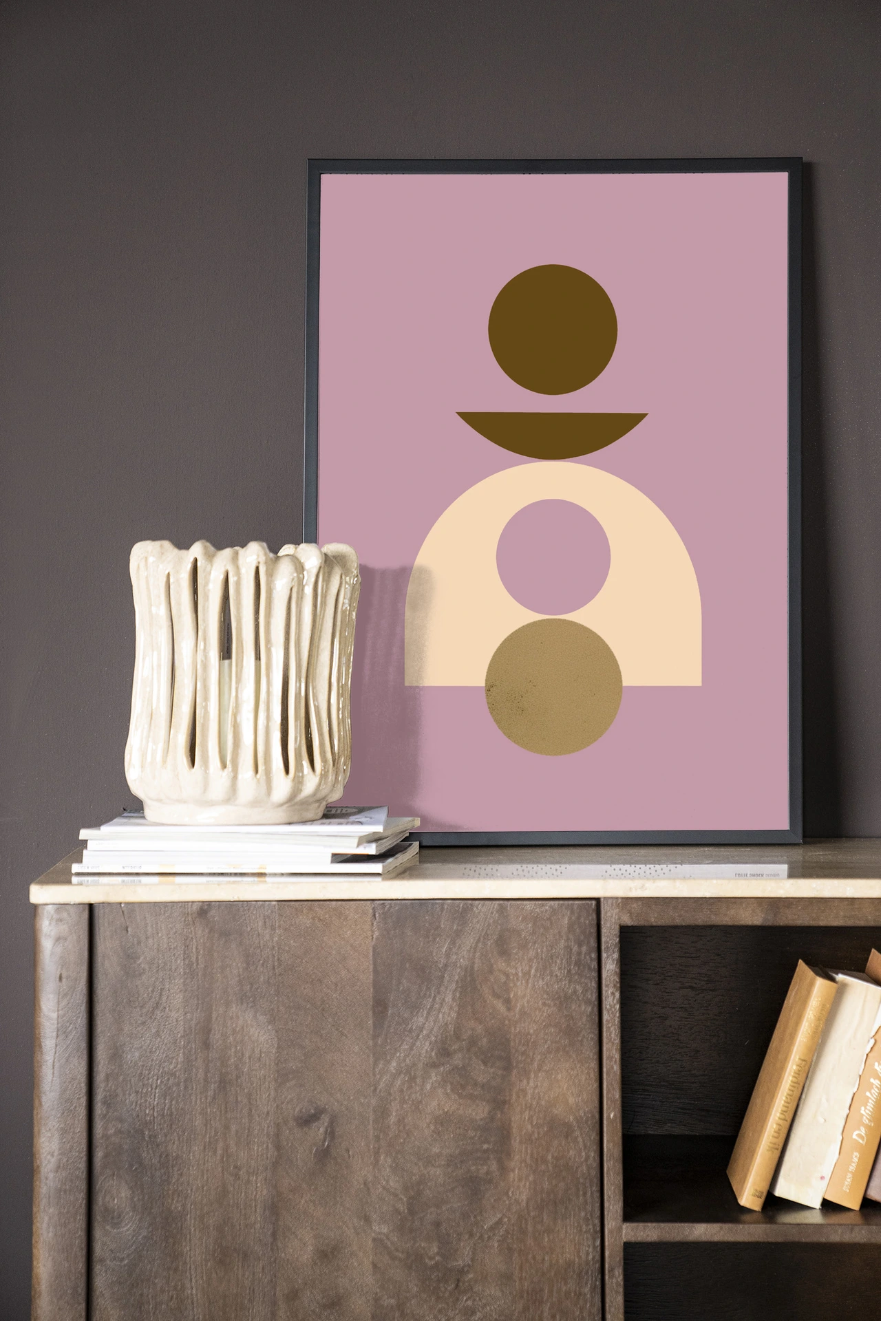 Het Wandkleed Forma 4 Lilac - Urban Cotton hangt boven een houten dressoir met boeken en een vaas