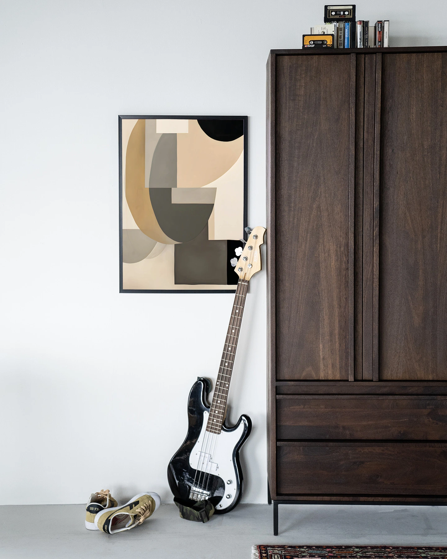 Wandkleed Tighten - Urban Cotton hangend aan een witte muur, met een basgitaar en schoenen eronder