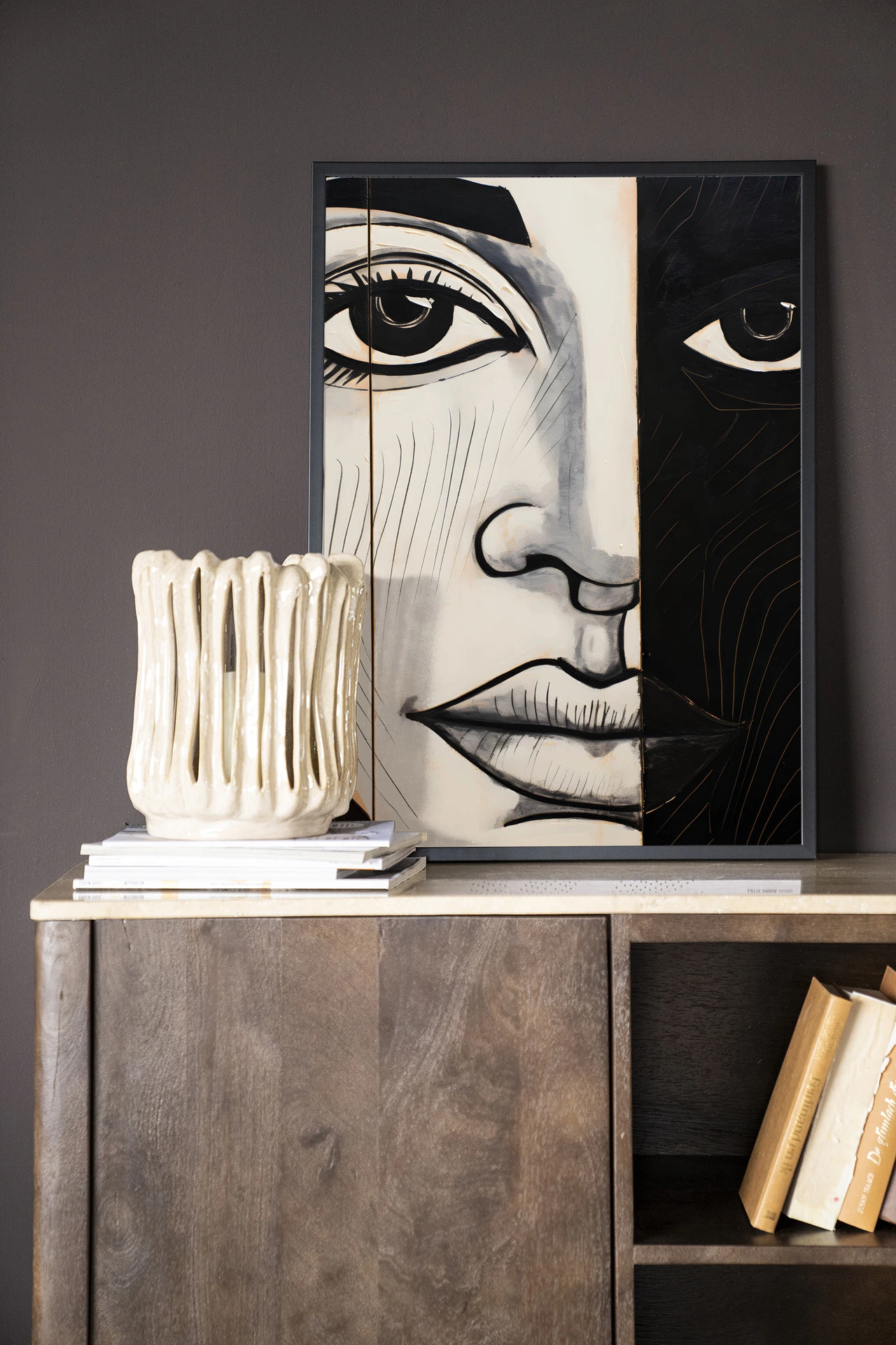 Wandkleed Contrast - Urban Cotton hangt boven een houten dressoir met boeken