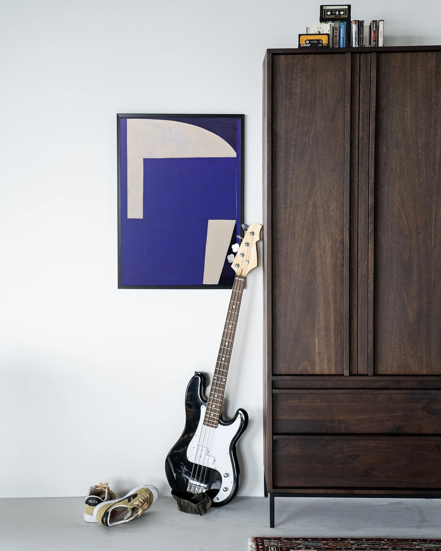 Art print Blues 2.0 - Urban Cotton hangt aan een witte muur naast een donkerbruine kast