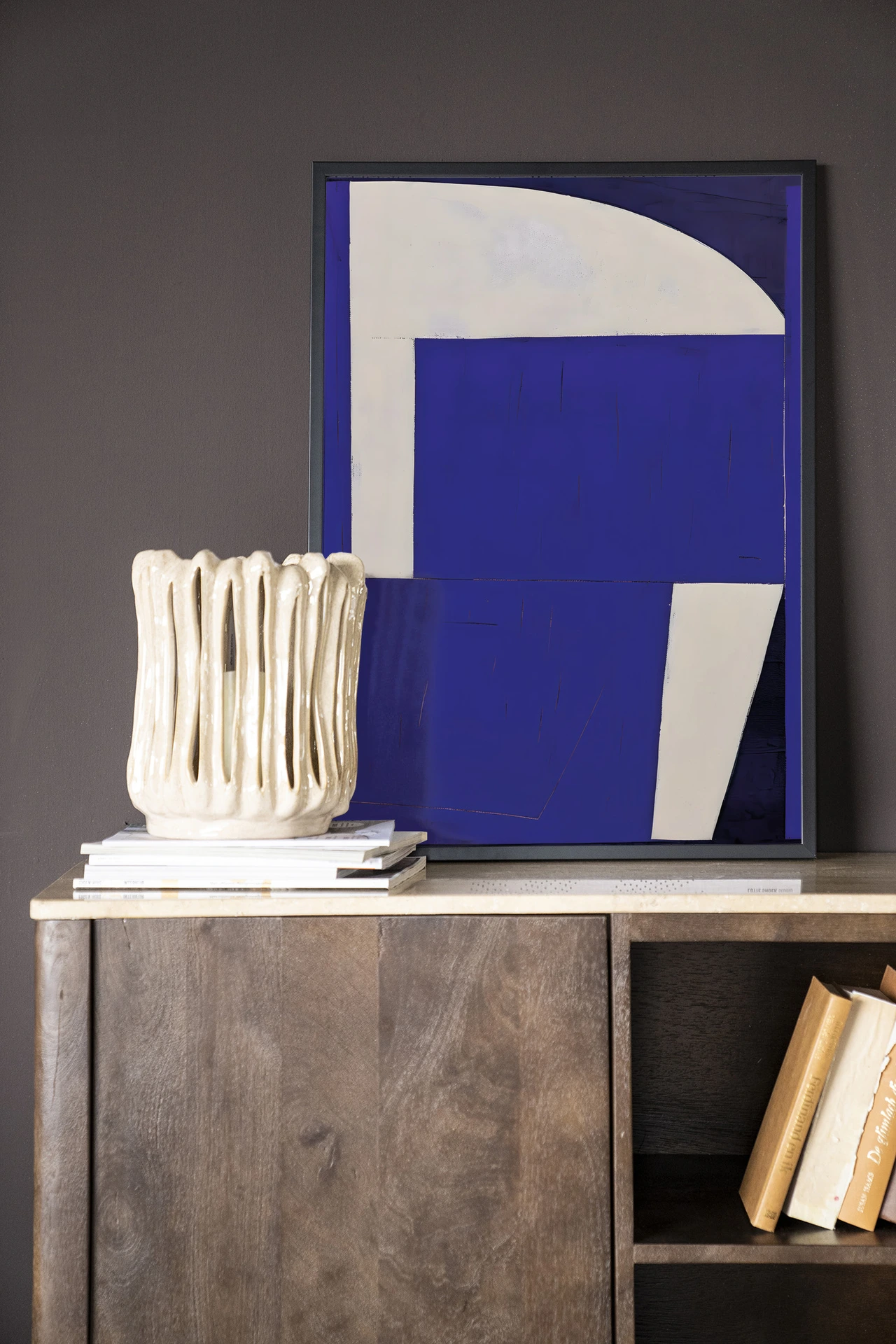 Art print Blues 2.0 - Urban Cotton in een zwarte lijst, staand op een houten dressoir met boeken