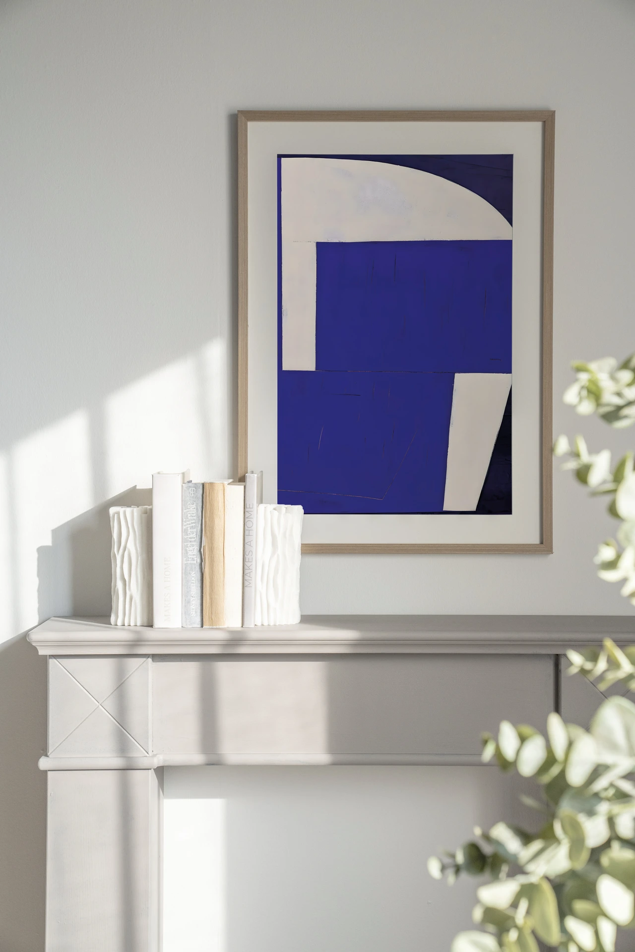 Art print Blues 2.0 - Urban Cotton in een lijst boven een lichte schouw met boeken