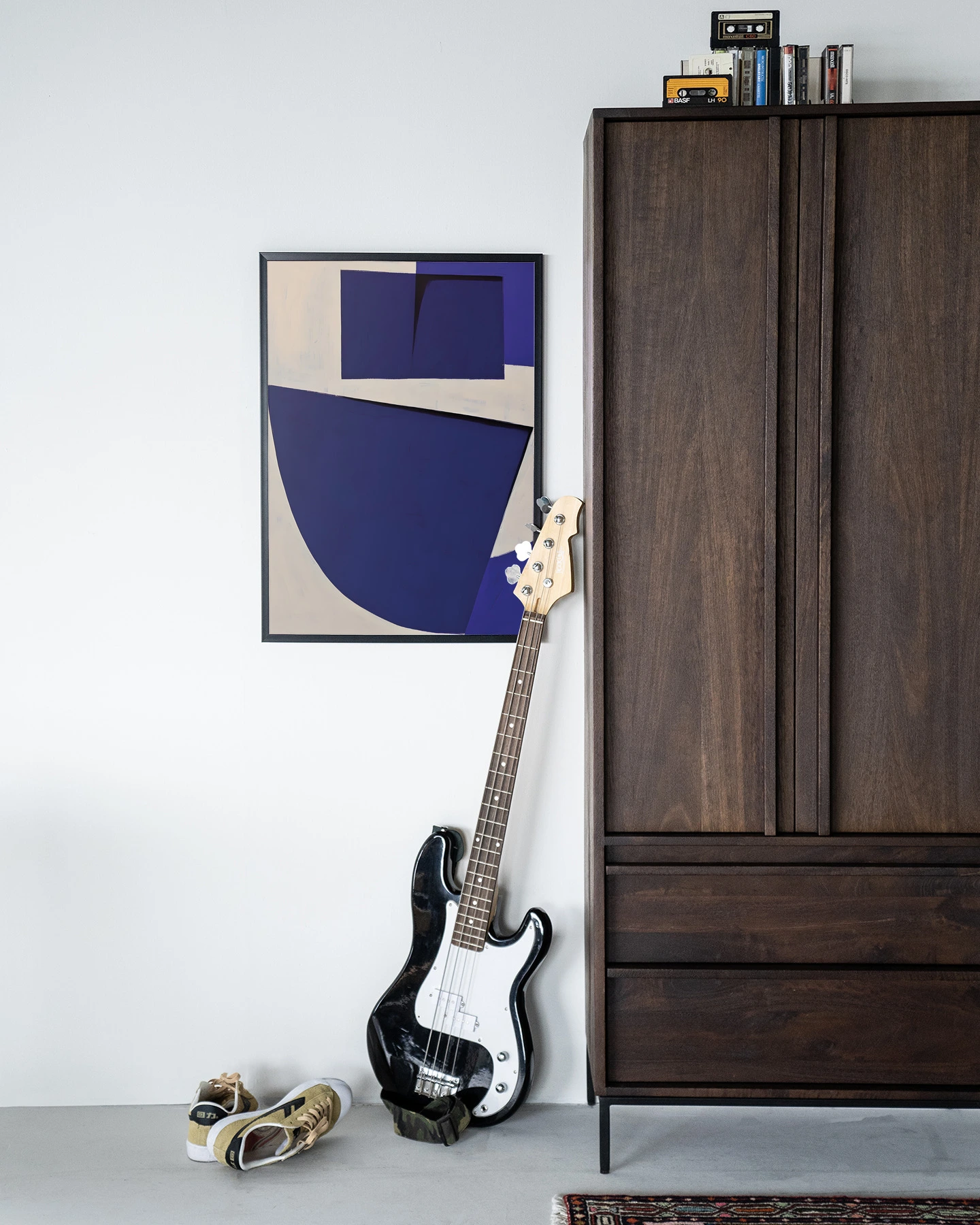De Art print Blues 3.0 - Urban Cotton hangt aan een witte muur naast een donkerbruine kast