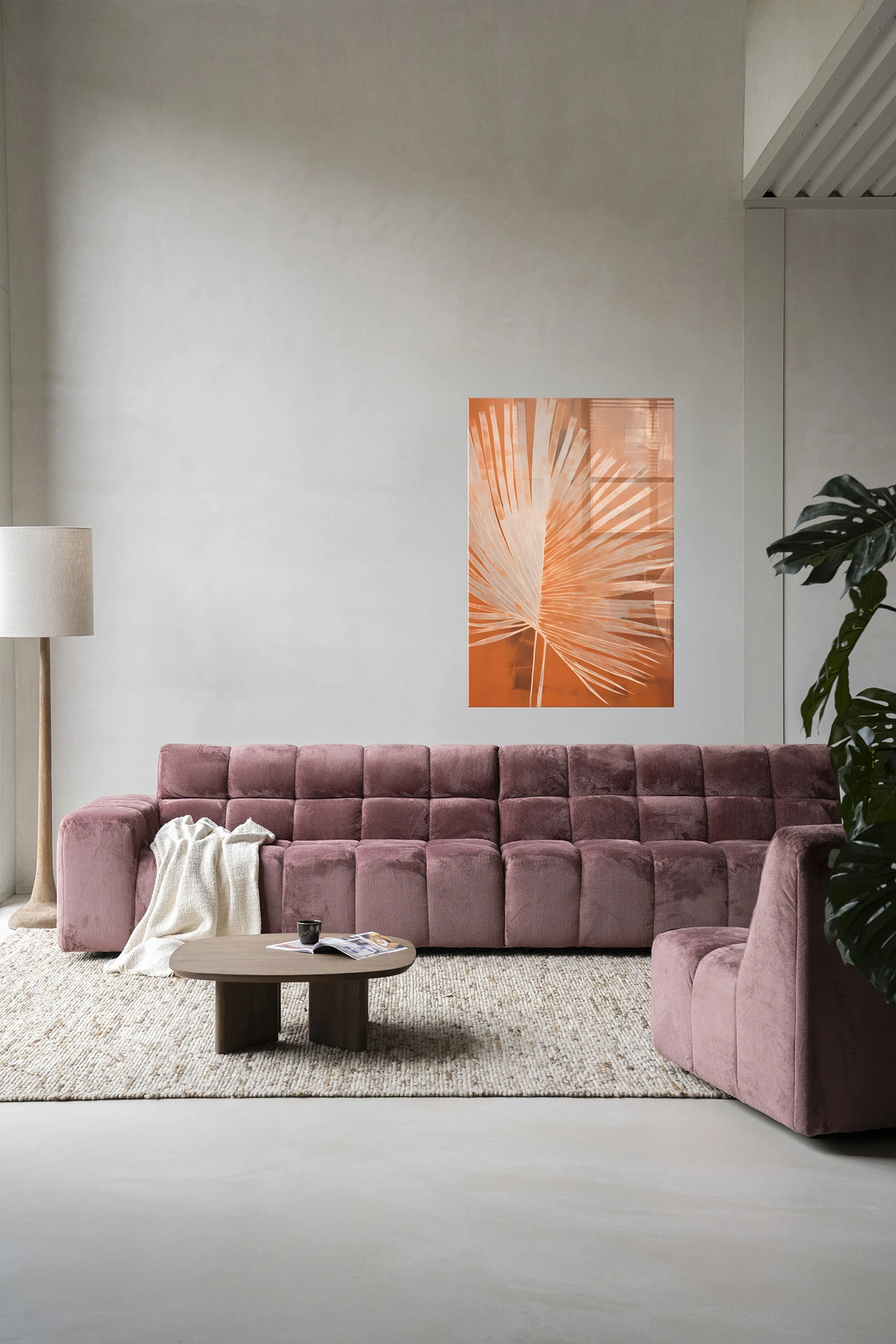 Wandkleed Rusty Palm - Urban Cotton hangt boven een roze bank in een moderne woonkamer